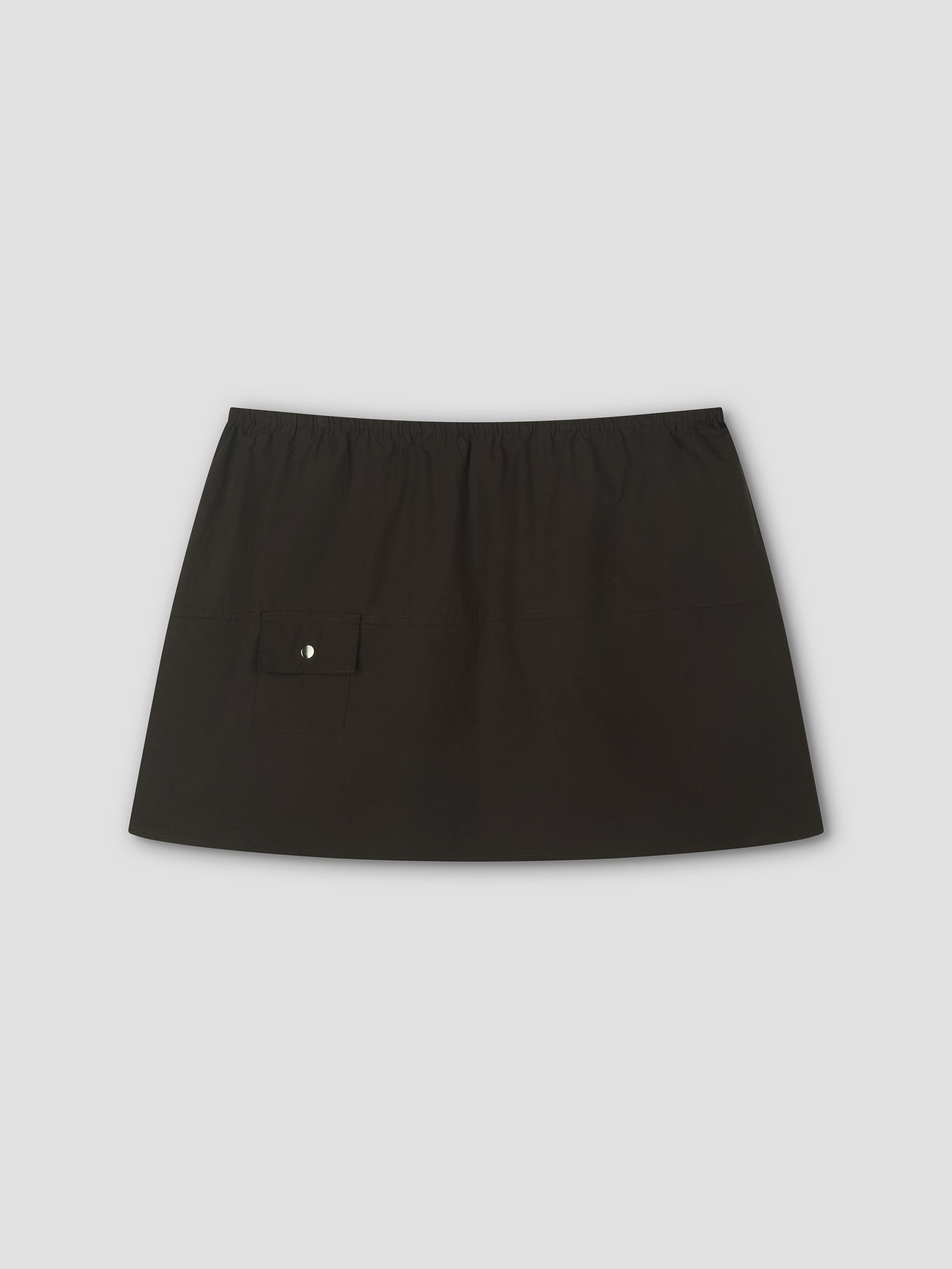 The Pocket Skirt is a plain black mini skirt with an elastic waistband and a small flap pocket with a button on the left side, shown on a light gray background.