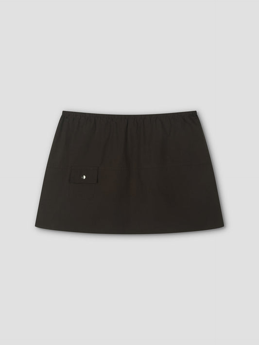The Pocket Skirt is a plain black mini skirt with an elastic waistband and a small flap pocket with a button on the left side, shown on a light gray background.