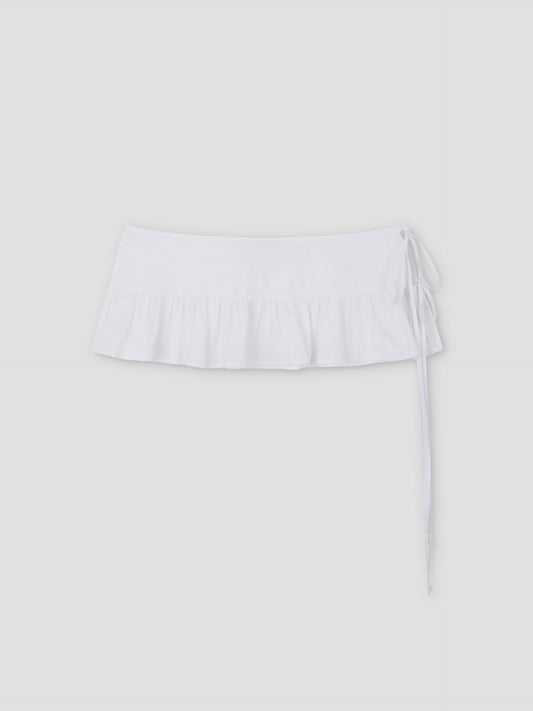 The Flounce Belt is a white mini skirt featuring a ruffled hem and side tie, shown against a plain light gray background.