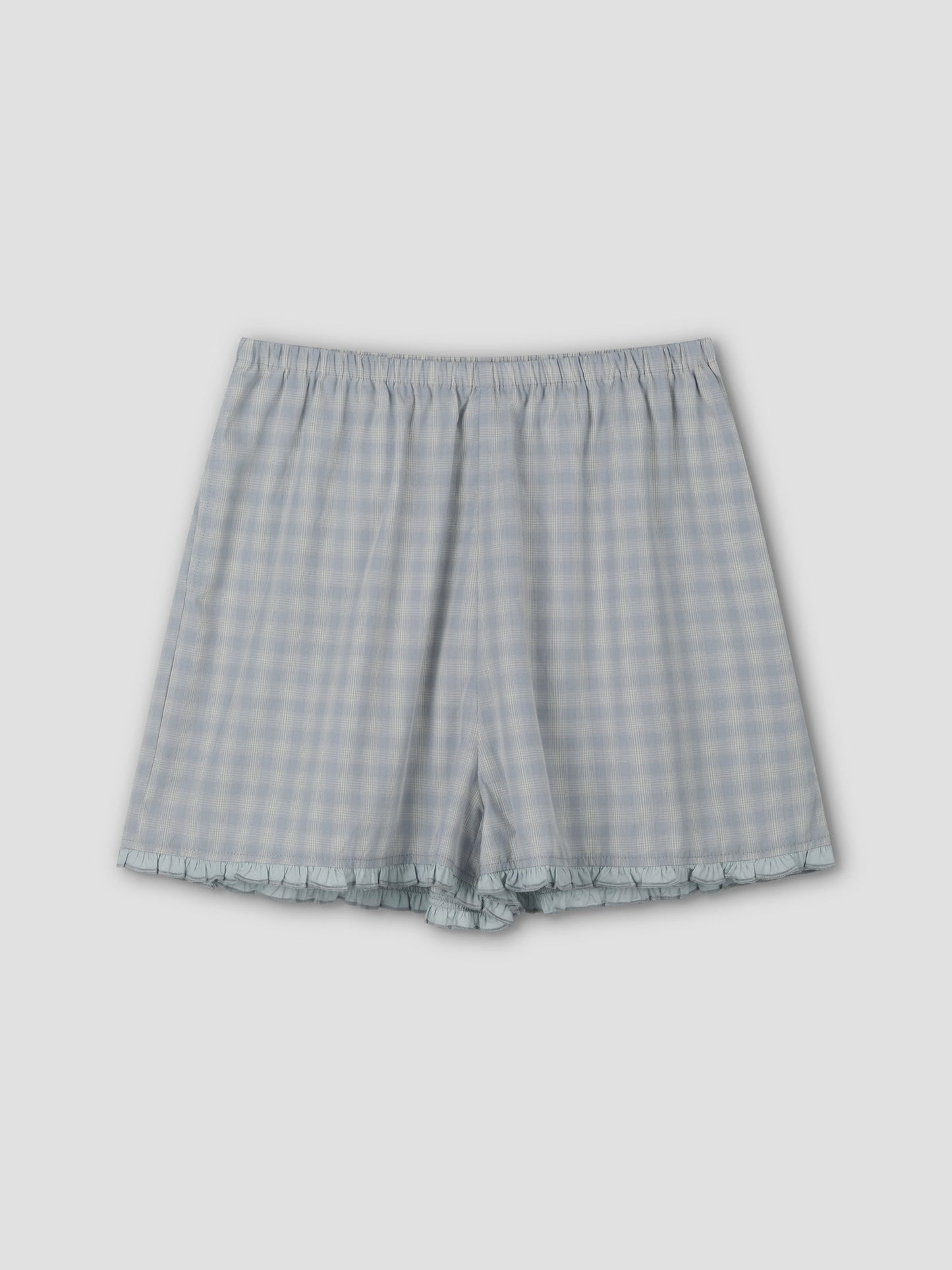 The Simple Short - Blue Check features a relaxed fit, elastic waistband, and subtle ruffle trim at the hem, shown flat on a plain light gray background.