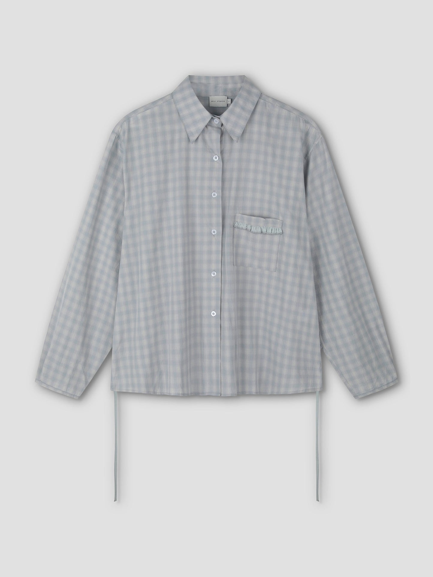 The Day Shirt - Blue Check features a light blue and white gingham pattern, boxy fit, long sleeves, collar, chest pocket with ruffle detail, and side ties. Shown as a button-up shirt on a plain light background.