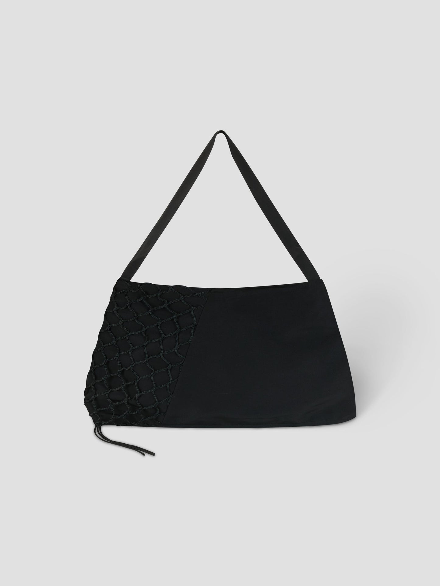 The Net Contrast Bag - Black by Deiji Studios features a wide strap, a textured net-like left side, and a smooth right side. Crafted from recycled polyester, it’s displayed against a plain light gray background.
