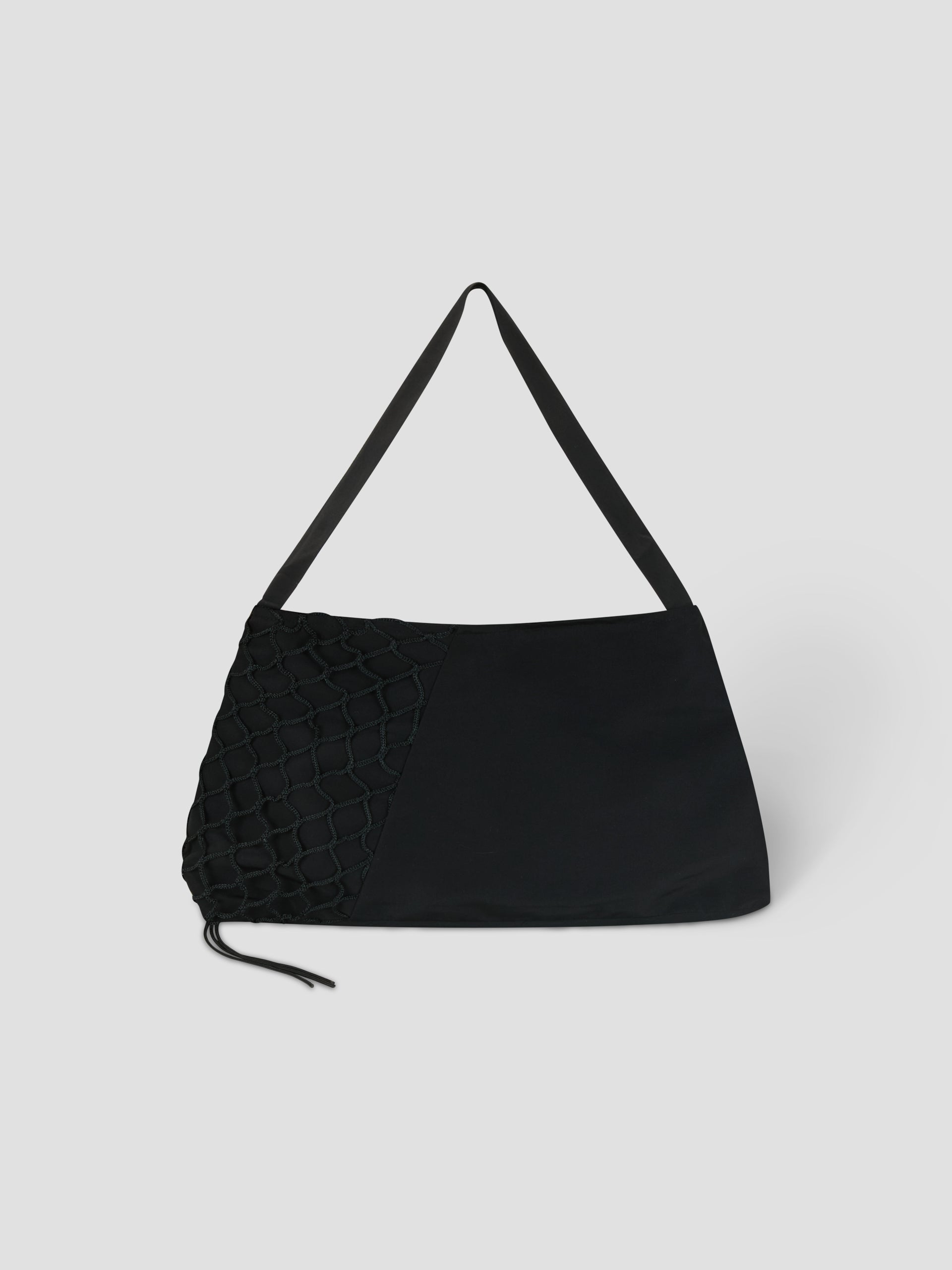 The Net Contrast Bag - Black by Deiji Studios features a wide strap, a textured net-like left side, and a smooth right side. Crafted from recycled polyester, it’s displayed against a plain light gray background.