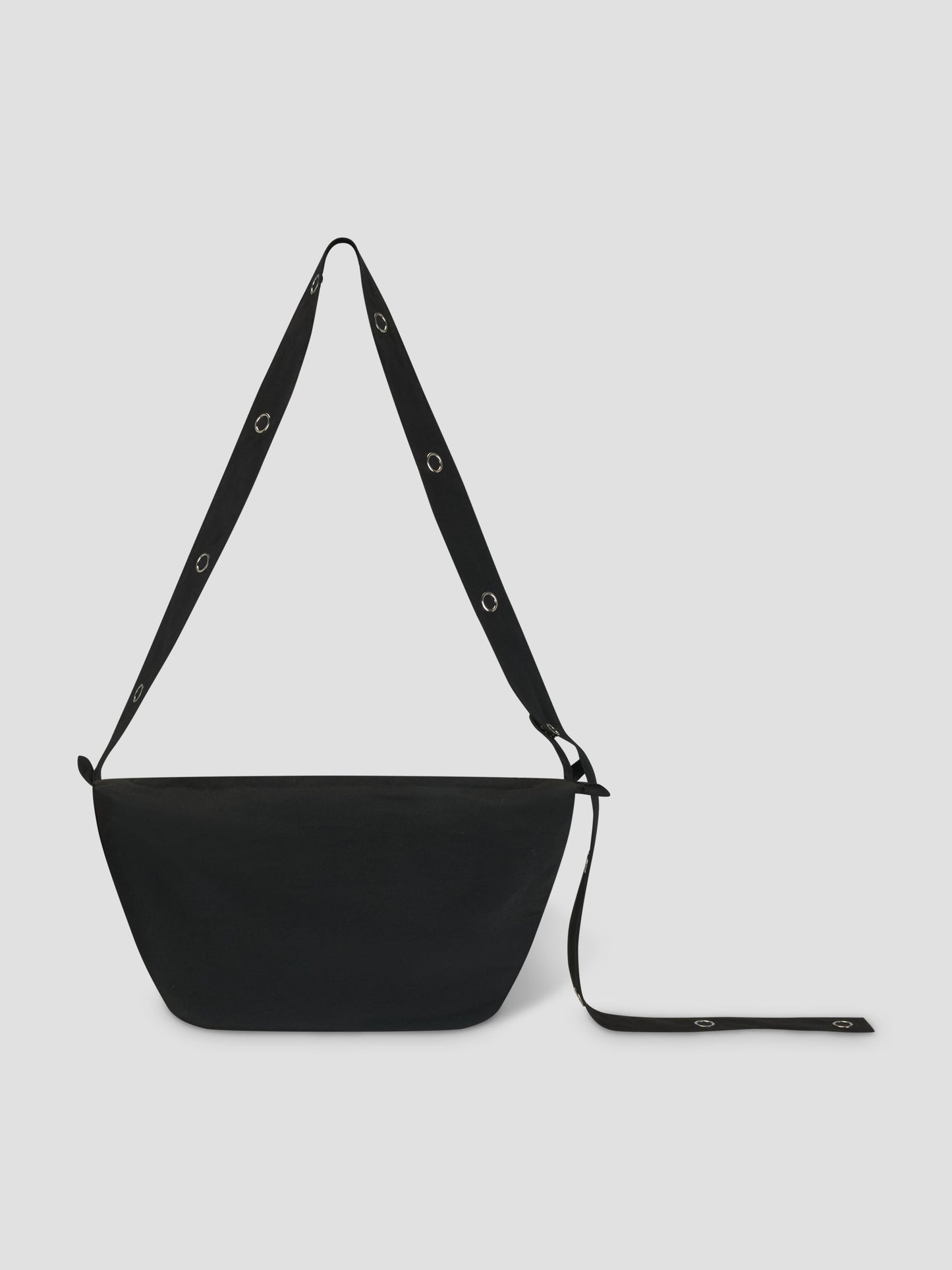 The Snap Belt Bag - Black by Deiji Studios is crafted from recycled polyester with a wide adjustable strap and metal grommets. The minimalist bag is shown against a light gray background.