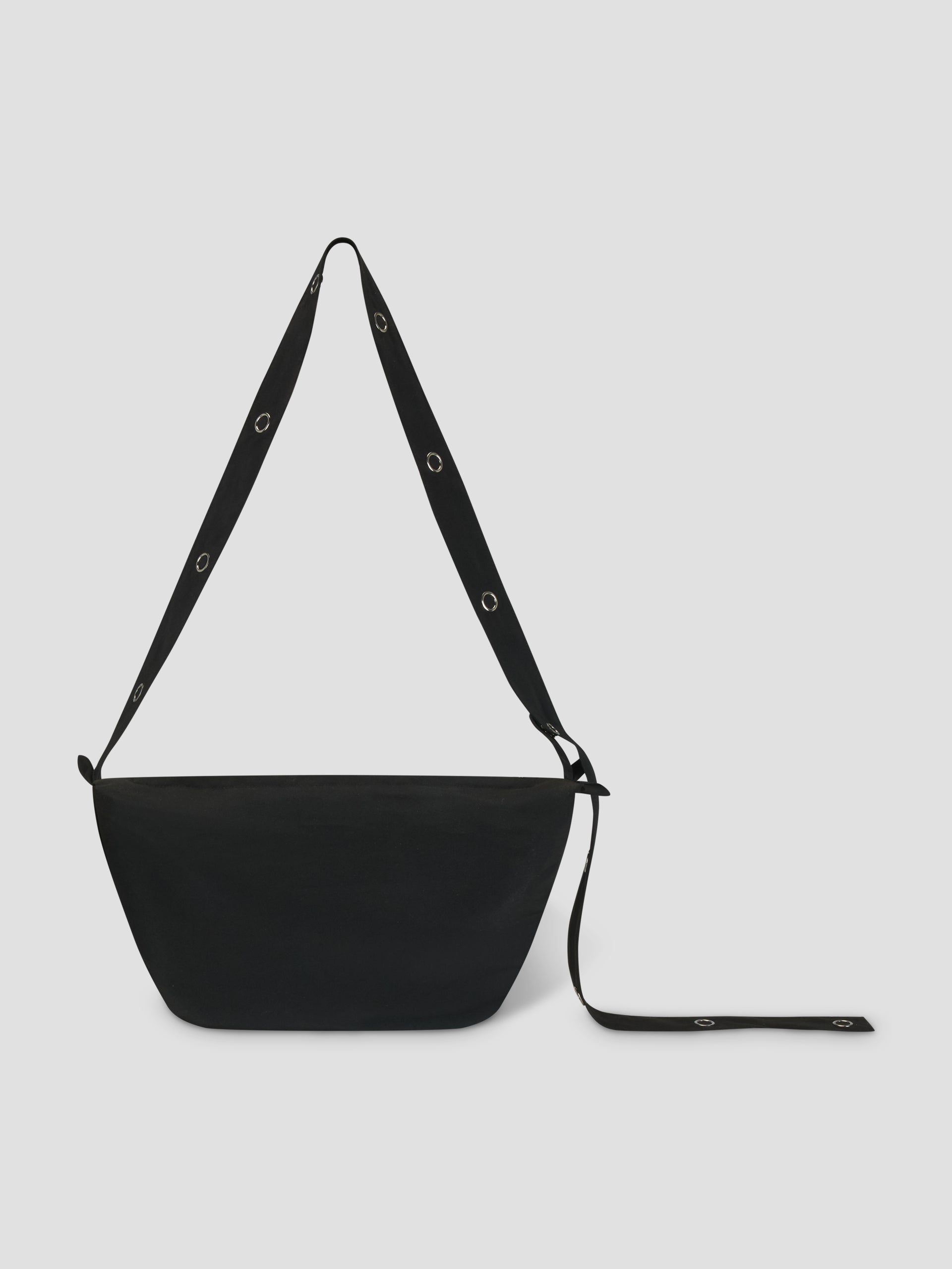 The Snap Belt Bag - Black by Deiji Studios is crafted from recycled polyester with a wide adjustable strap and metal grommets. The minimalist bag is shown against a light gray background.