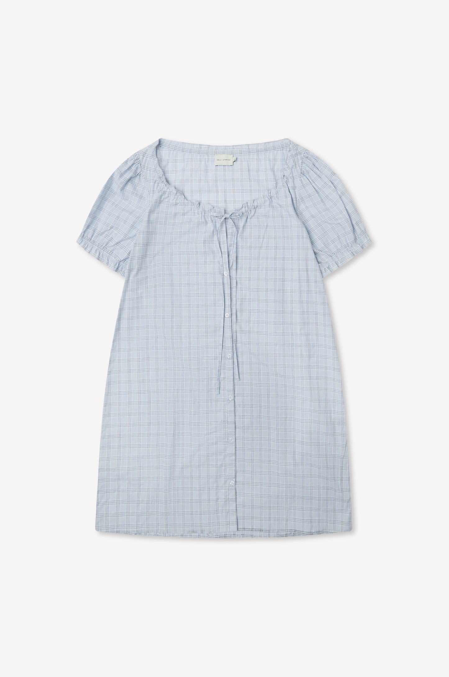 The Buttoned Mini Dress - Powder Check by Deiji Studios in light blue features a round neckline, front collar tie detail, and powder check pattern, shown laid flat on a white background.