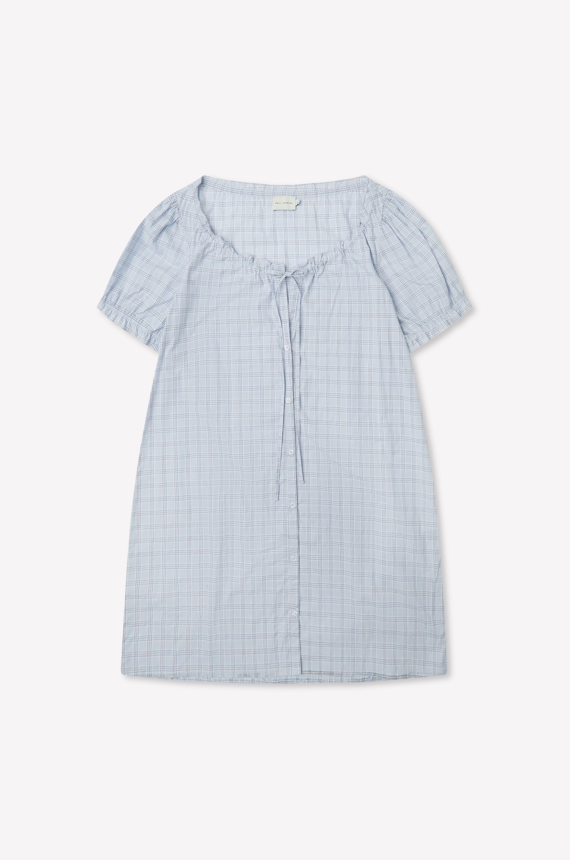 The Buttoned Mini Dress - Powder Check by Deiji Studios in light blue features a round neckline, front collar tie detail, and powder check pattern, shown laid flat on a white background.