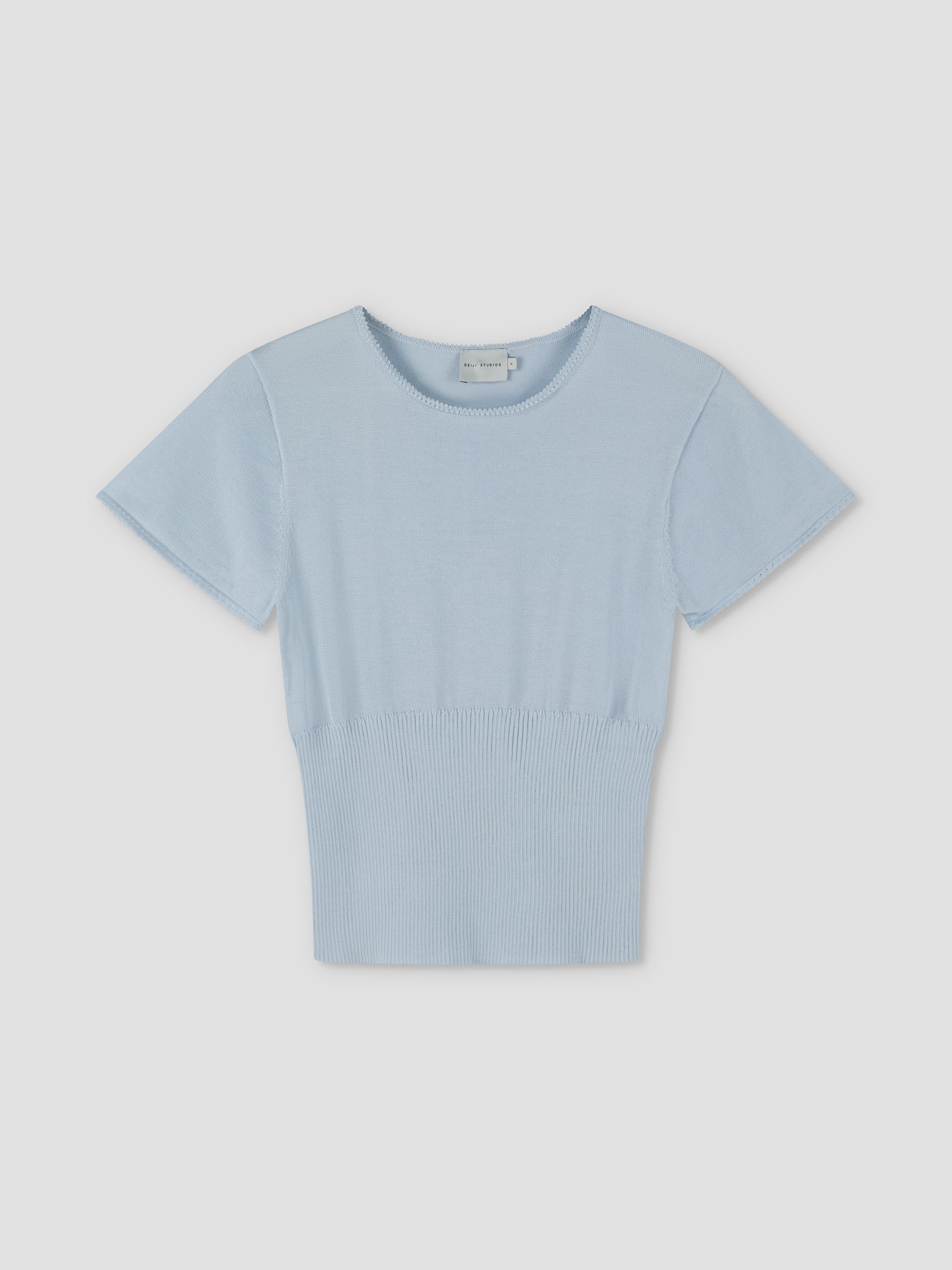 The Trim Knit Tee - Ice Blue by Deiji Studios features short sleeves, a round neckline, and a fitted ribbed waistband, displayed against a plain light background.