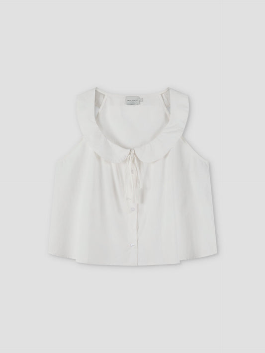 The Round Collar Top - White Texture by Deiji Studios is a sleeveless white top with a wide ruffled collar, front buttons, and a delicate bow tie at the neckline, shown against a plain light background.