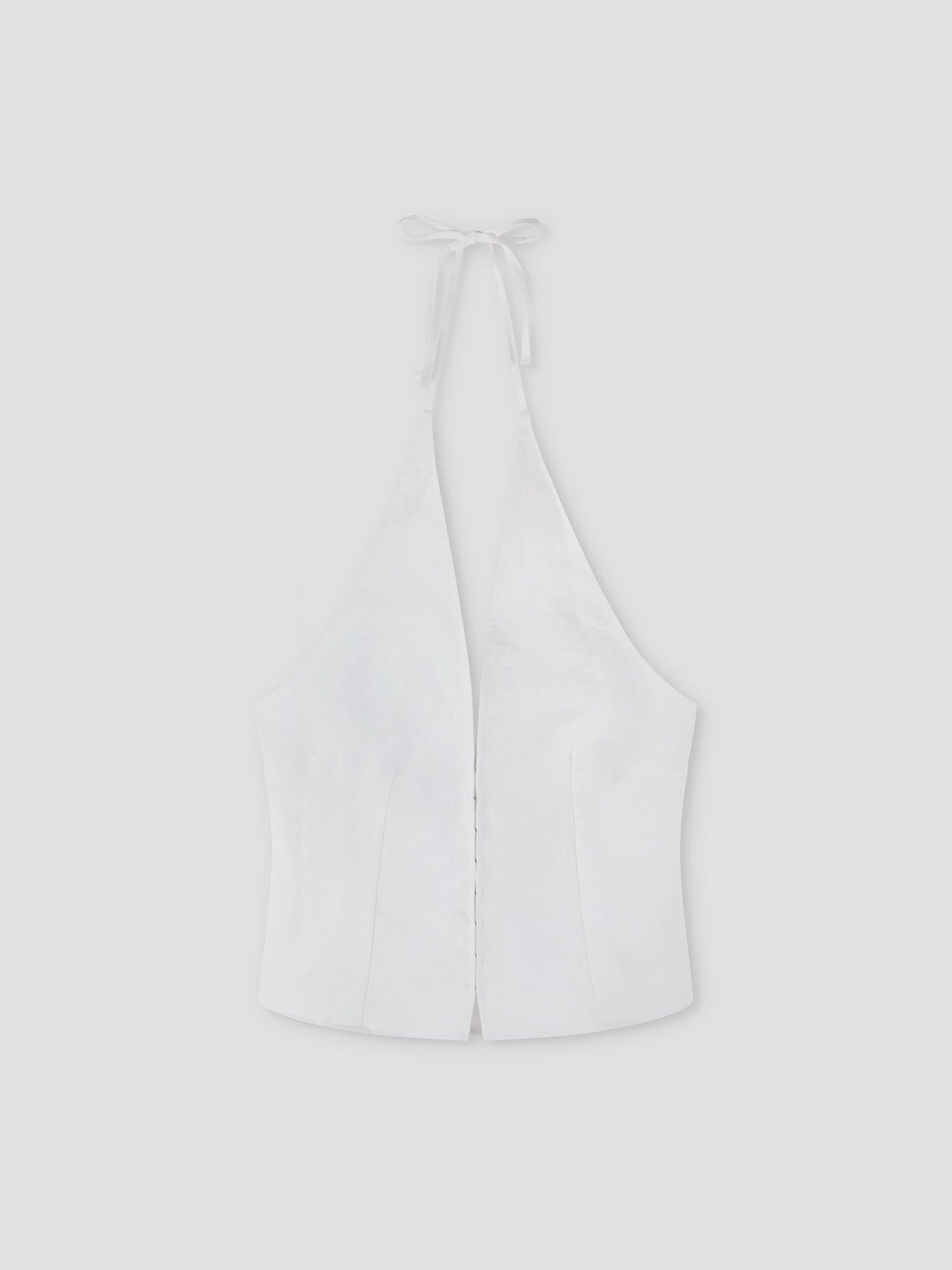 The Close Halter Top - White by Deiji Studios features a deep V neckline, fitted bodice, and open back with neck ties. Displayed on a plain light gray background, it highlights clean, minimalist elegance.