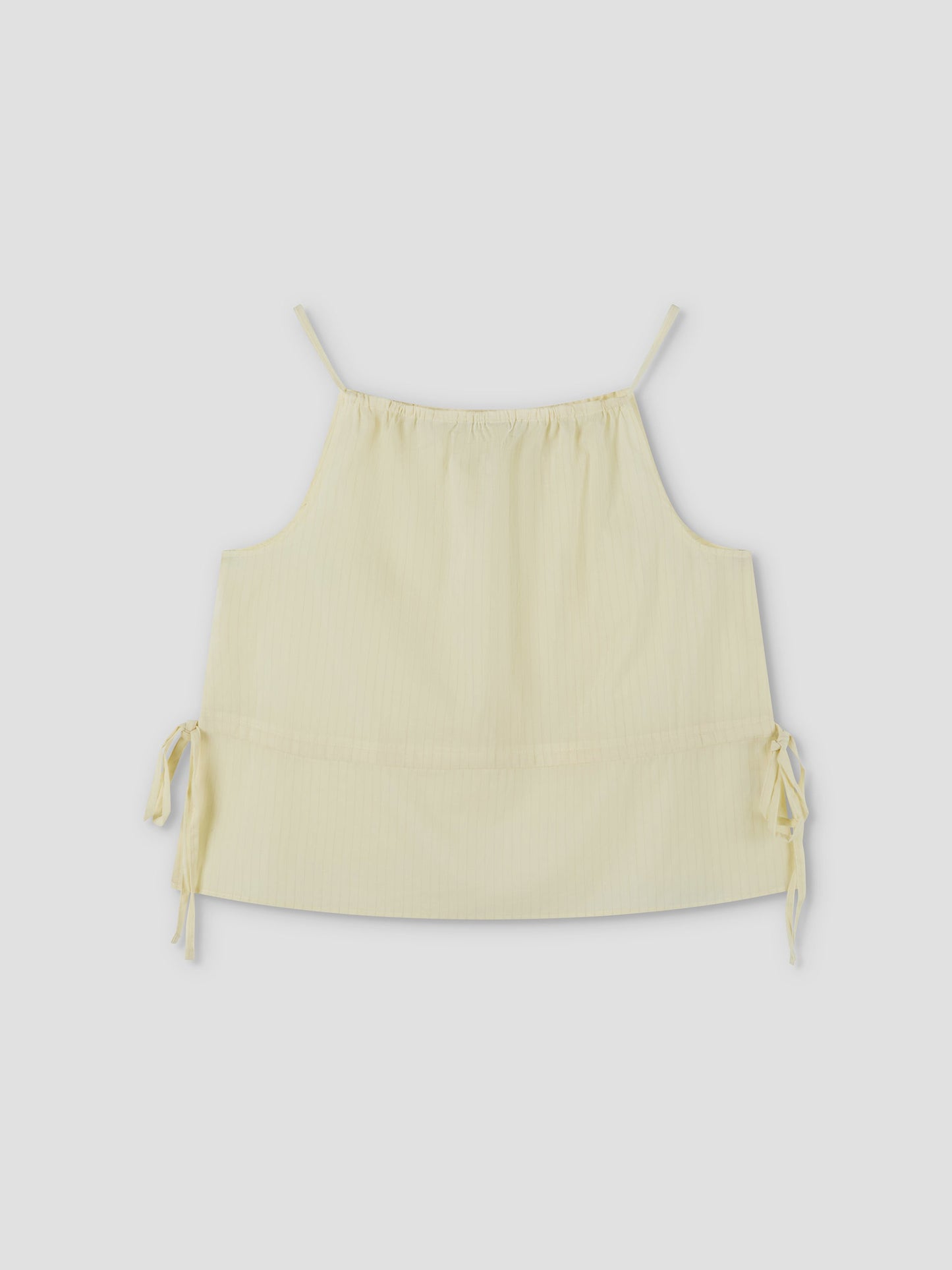 Waist Tie Top - Soft Yellow Stripe by Deiji Studios features a light yellow striped design, sleeveless cut, thin shoulder straps, adjustable neckline, and side waist ties. Shown against a plain light background.