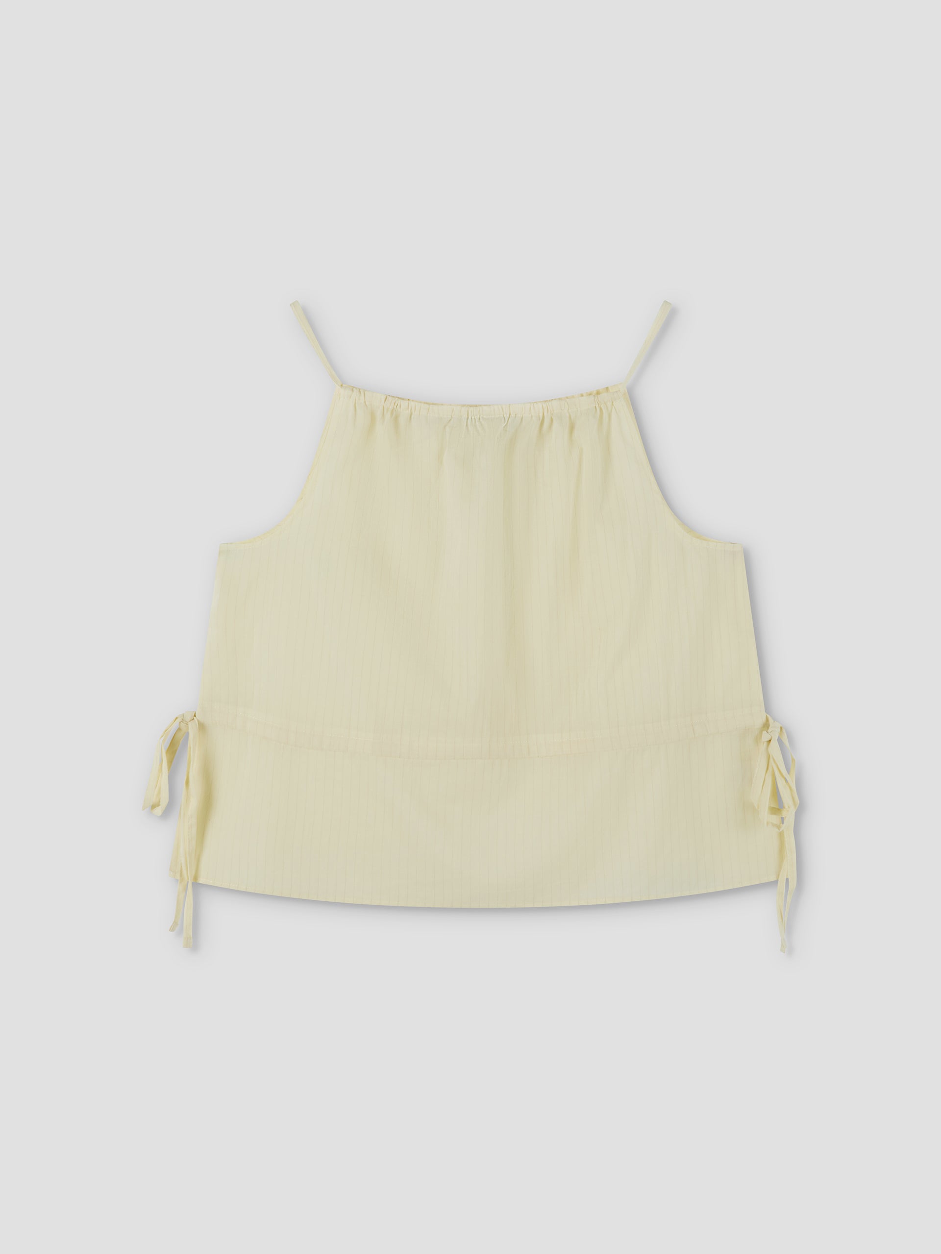 Waist Tie Top - Soft Yellow Stripe by Deiji Studios features a light yellow striped design, sleeveless cut, thin shoulder straps, adjustable neckline, and side waist ties. Shown against a plain light background.
