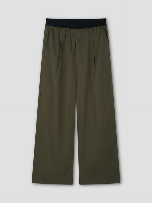 The Contrast Waist Pant - Olive by Deiji Studios features a black elastic waistband, relaxed wide-leg fit, side pockets, and front pleats, shown flat on a light gray background.
