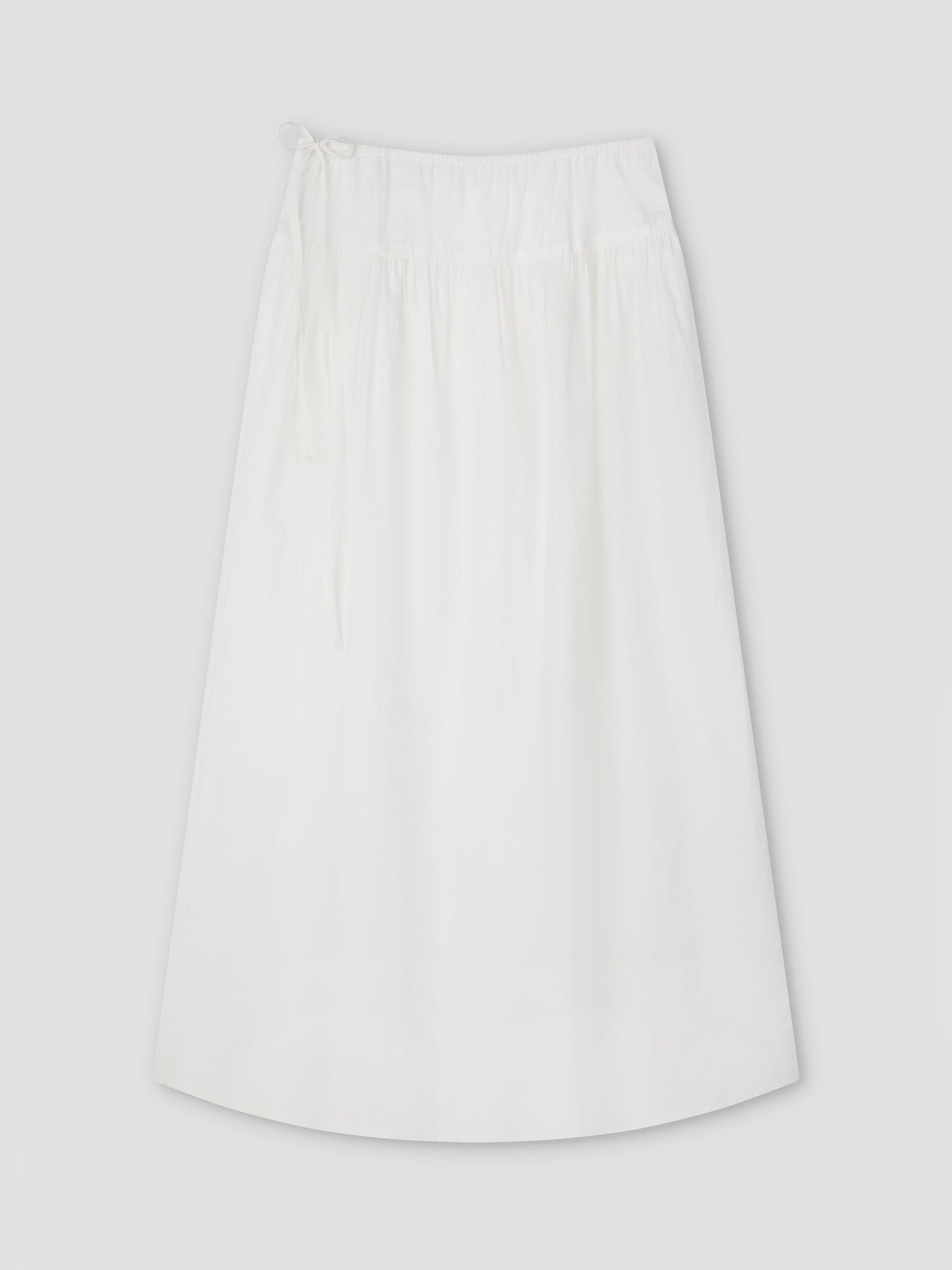 The Maxi Skirt - White Texture by Deiji Studios is a plain A-line maxi skirt with an elastic waistband and drawstring tie, shown laid flat on a light gray background.