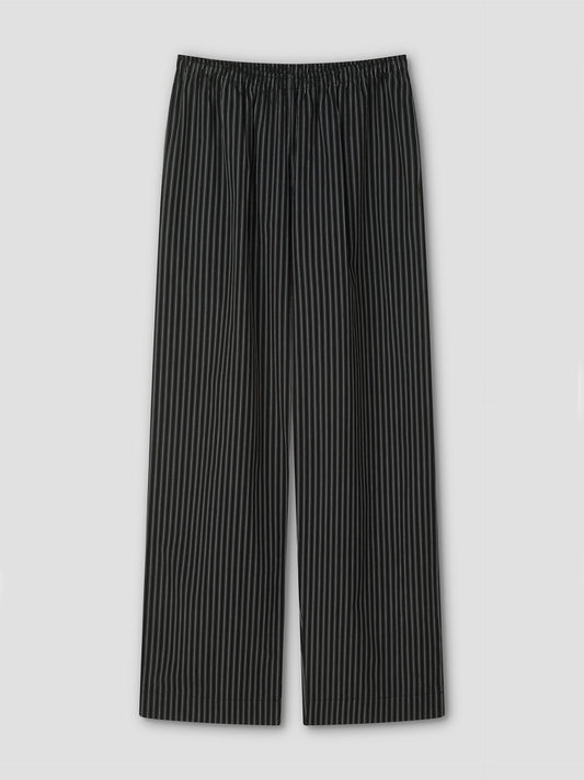 The Ease Trouser - Mono Stripe by Deiji Studios features black ankle-length design with thin white vertical pinstripes, an elastic waistband, and wide legs for a relaxed fit, shown flat on a light gray background.