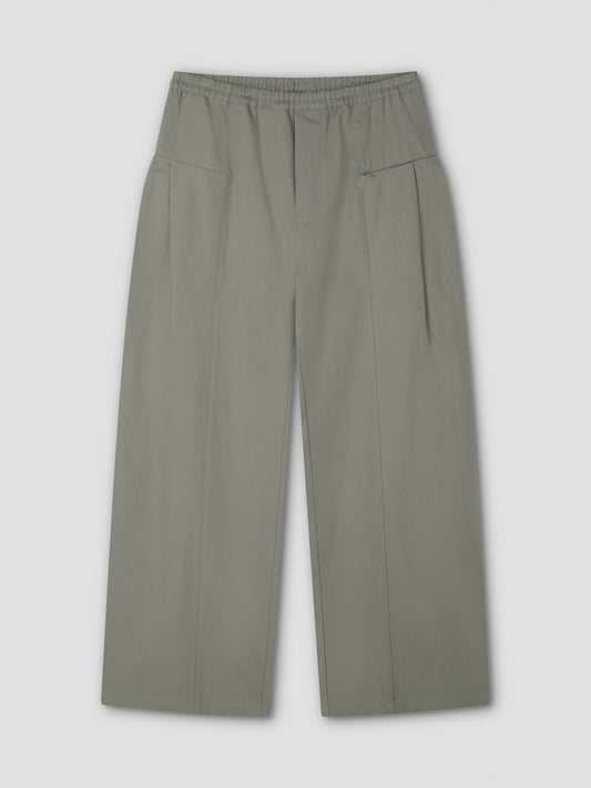The Pleat Pant - Sage Grey by Deiji Studios features a wide-leg, high-waisted design with an elastic waistband, subtle pleats, and two large front pockets, shown laid flat on a light gray background.