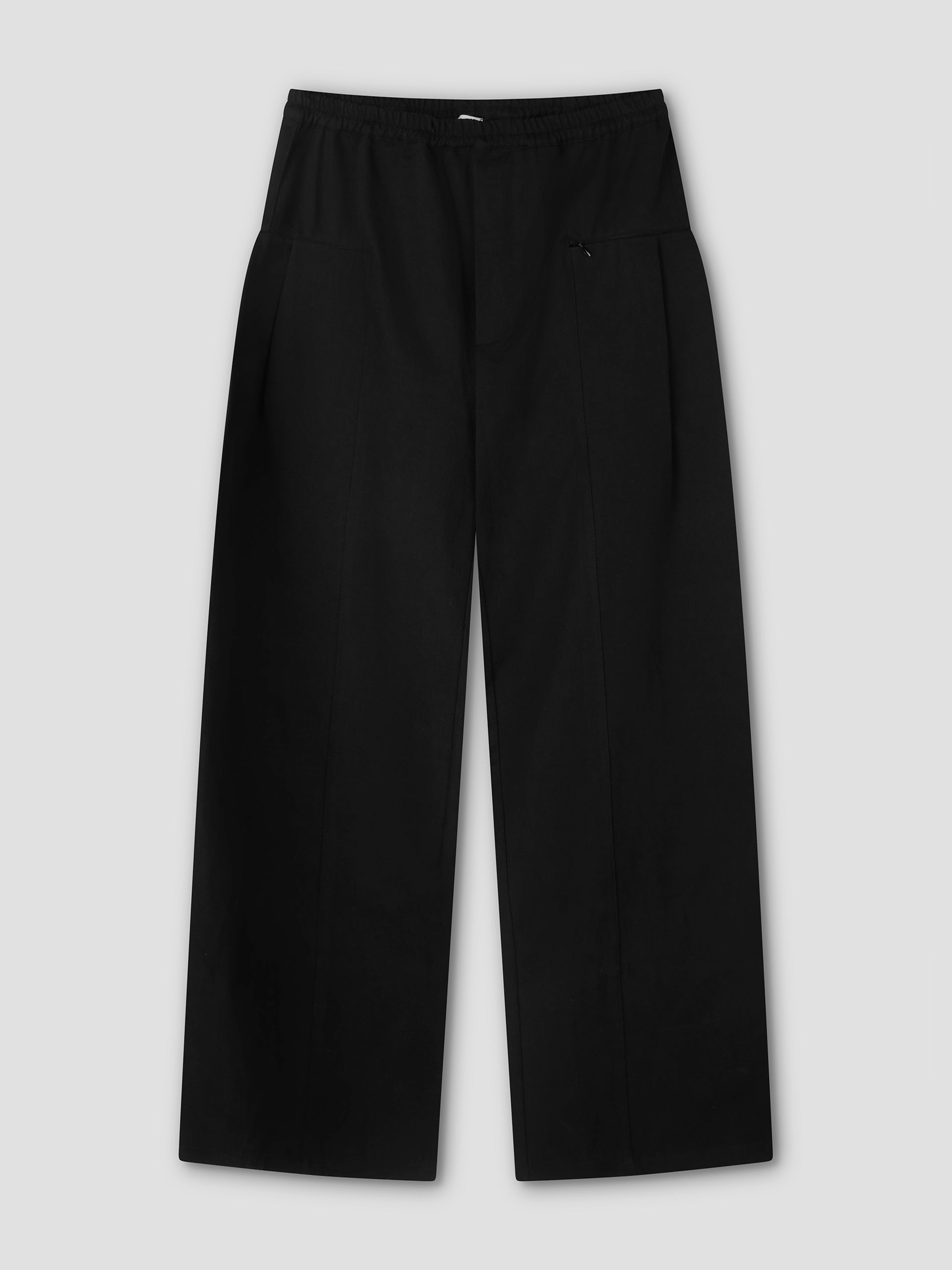 The Pleat Pant - Black from Deiji Studios, featuring a relaxed fit, elastic waistband, and subtle front seam details, is displayed laid flat on a light gray background.