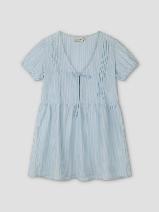 The V Pleat Dress - Lake Blue Stripe from Deiji Studios is a lightweight mini dress with short sleeves, thin vertical white stripes, a tie V-neckline, gathered waist, and v pleat accents, shown on a flat light background.