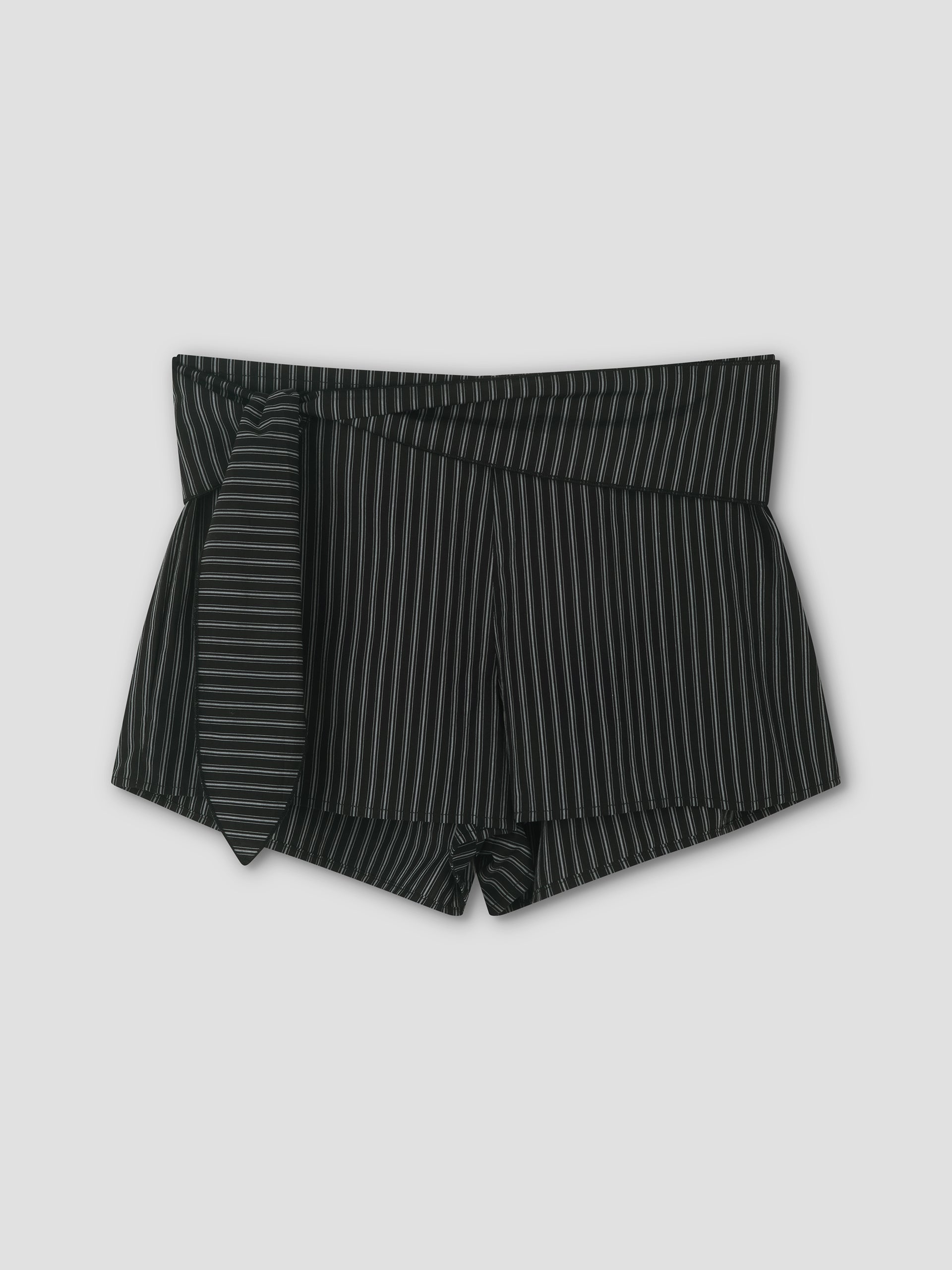 The Belted Short - Mono Stripe features black high-waisted mini shorts with thin white vertical pinstripes and a matching fabric belt tied on the left, shown against a plain light gray background.