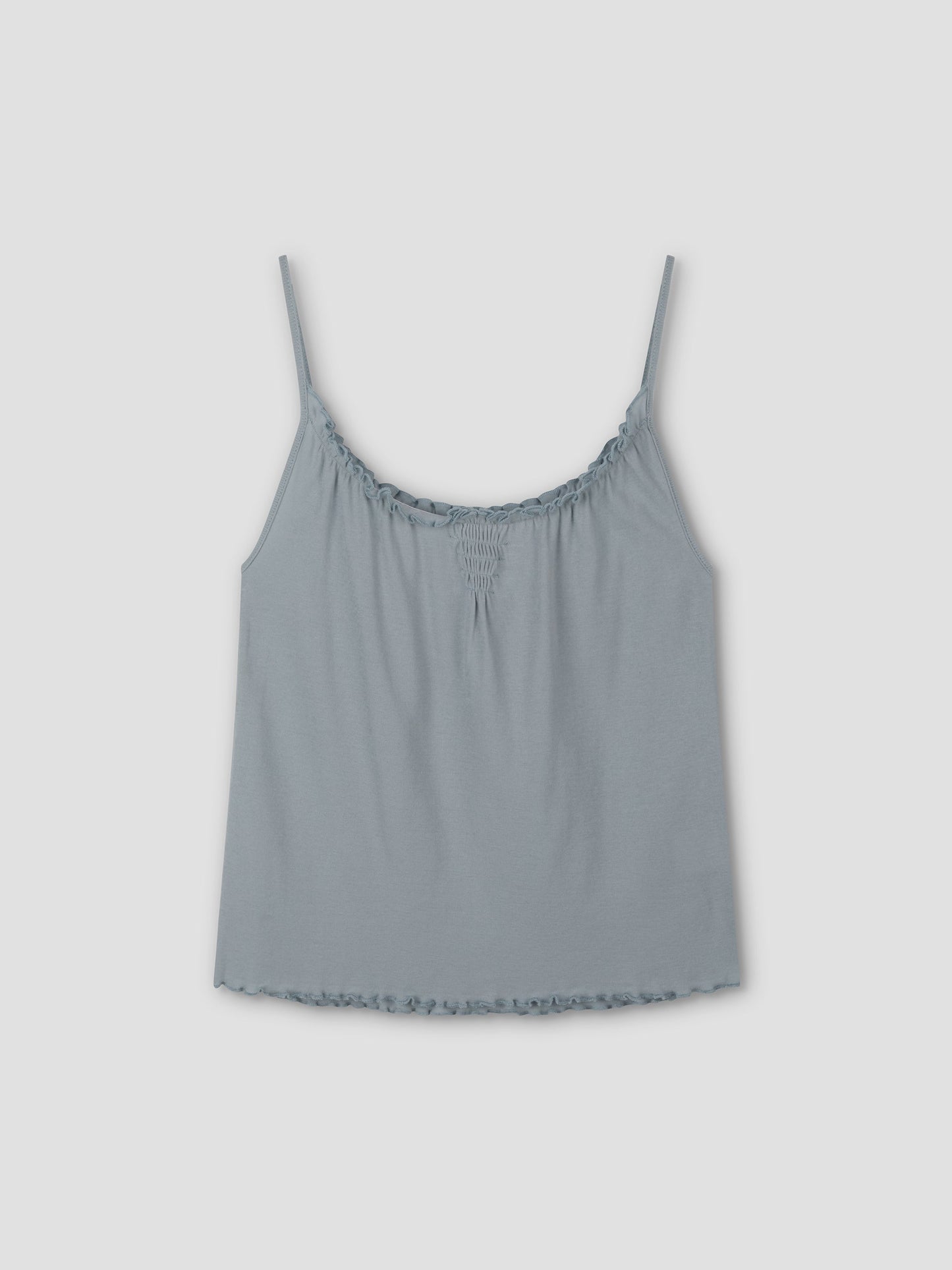 The Cotton Flounce Tank - Baby Blue by Deiji Studios features thin spaghetti straps, gathered neckline, and ruffled hem, shown against a plain light gray background.