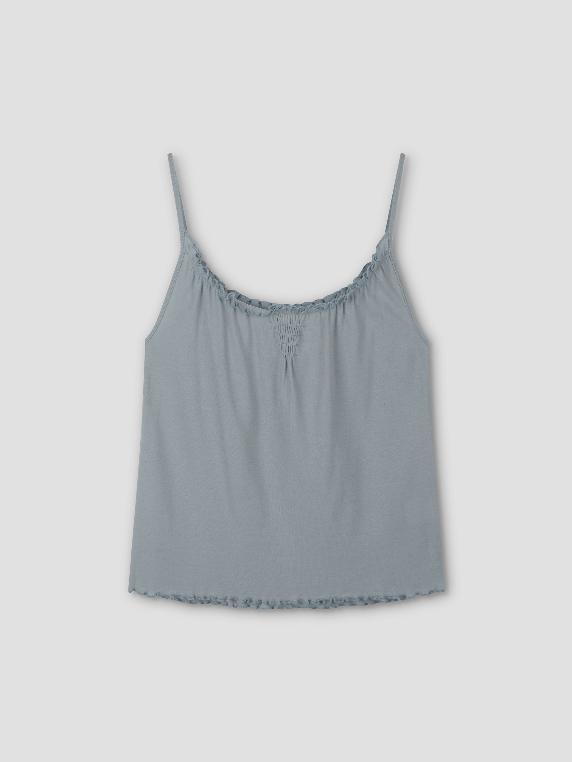 The Cotton Flounce Tank - Baby Blue by Deiji Studios features thin spaghetti straps, gathered neckline, and ruffled hem, shown against a plain light gray background.