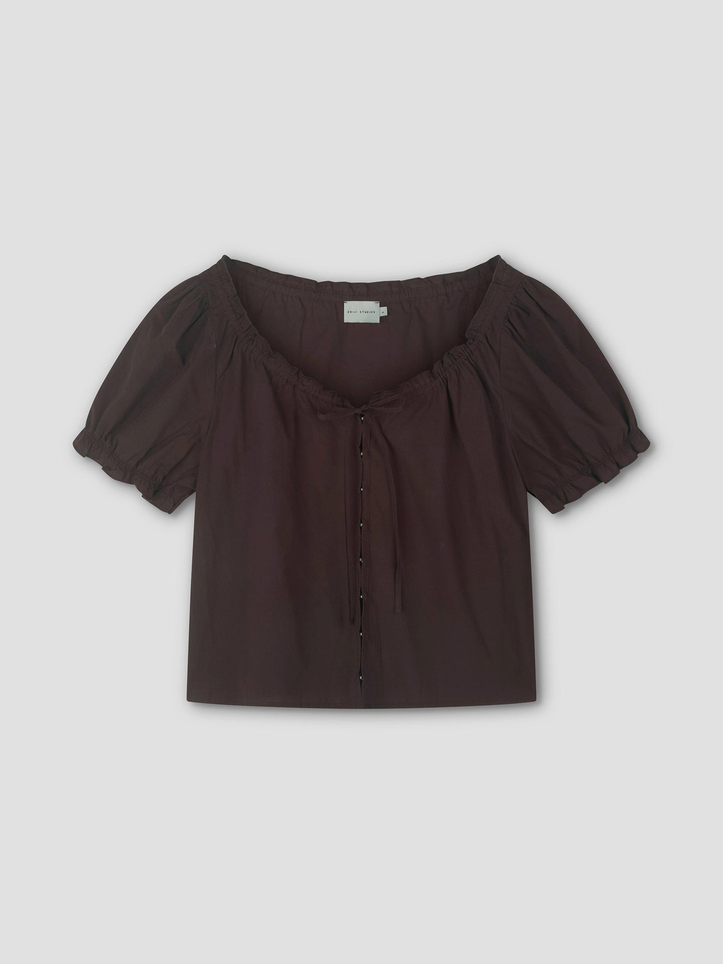 The Close Shirt - Sepia by Deiji Studios is a short-sleeved, dark brown blouse featuring a square neckline, puff sleeves with gathers, a drawstring neckline tie, and button-down front, shown on a plain light background.