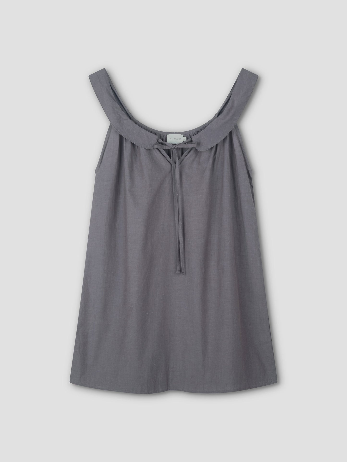 Sleeveless, loose-fitting Rounded Neck Dress in Currant by Deiji Studios features a wide neckline and small front tie. Crafted from lightweight fabric that drapes softly, shown against a plain light background.