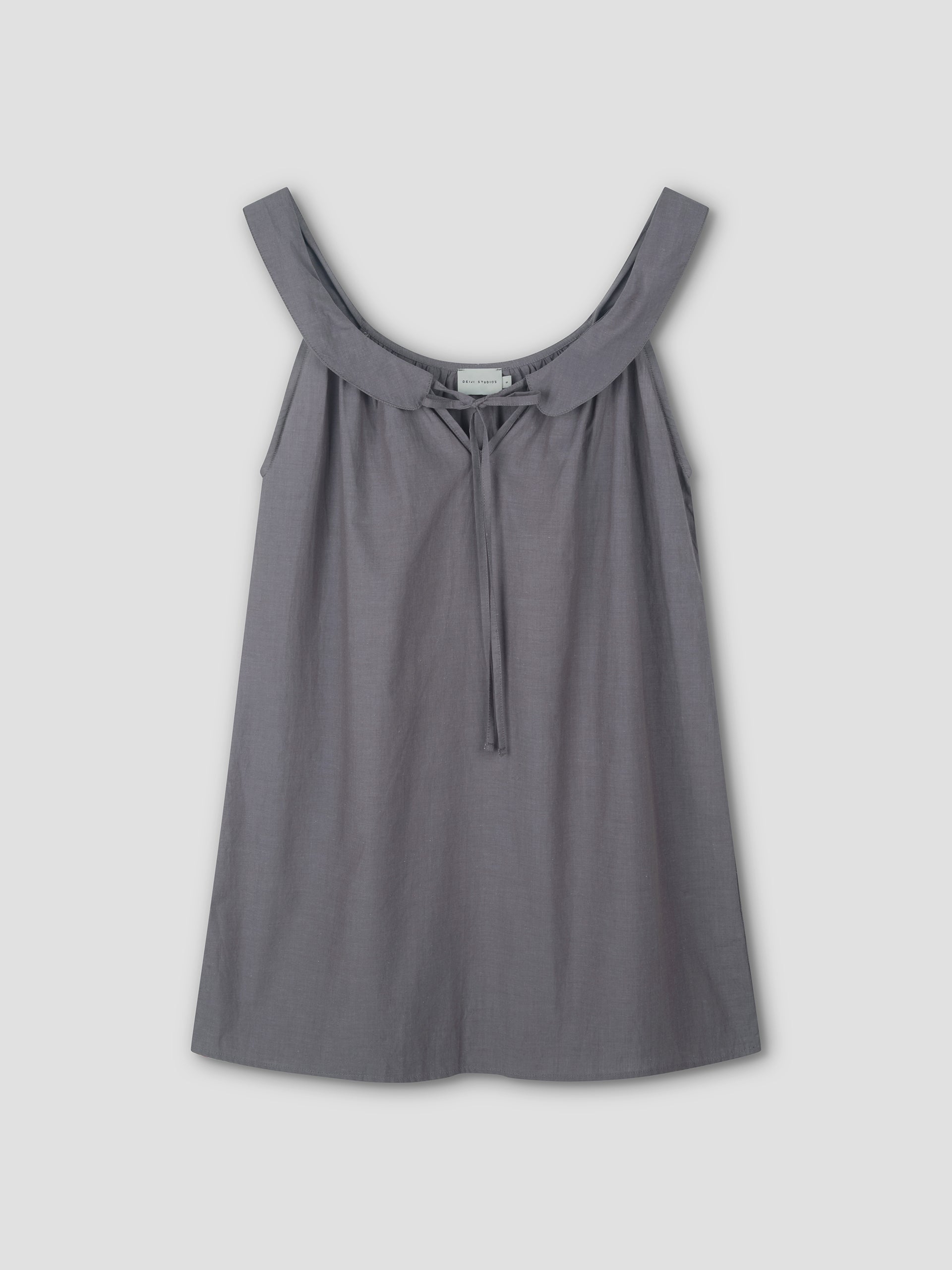 Sleeveless, loose-fitting Rounded Neck Dress in Currant by Deiji Studios features a wide neckline and small front tie. Crafted from lightweight fabric that drapes softly, shown against a plain light background.
