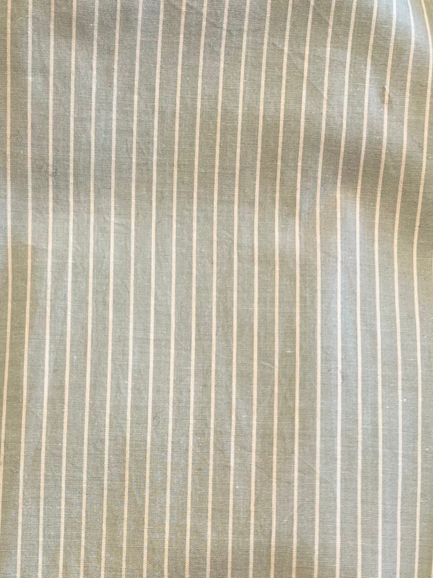 Close-up of light organic cotton fabric from Deiji Studios’ Ease Trouser - Pistachio Stripe, showing thin white vertical pinstripes and subtle wrinkles—ideal for timeless comfort.