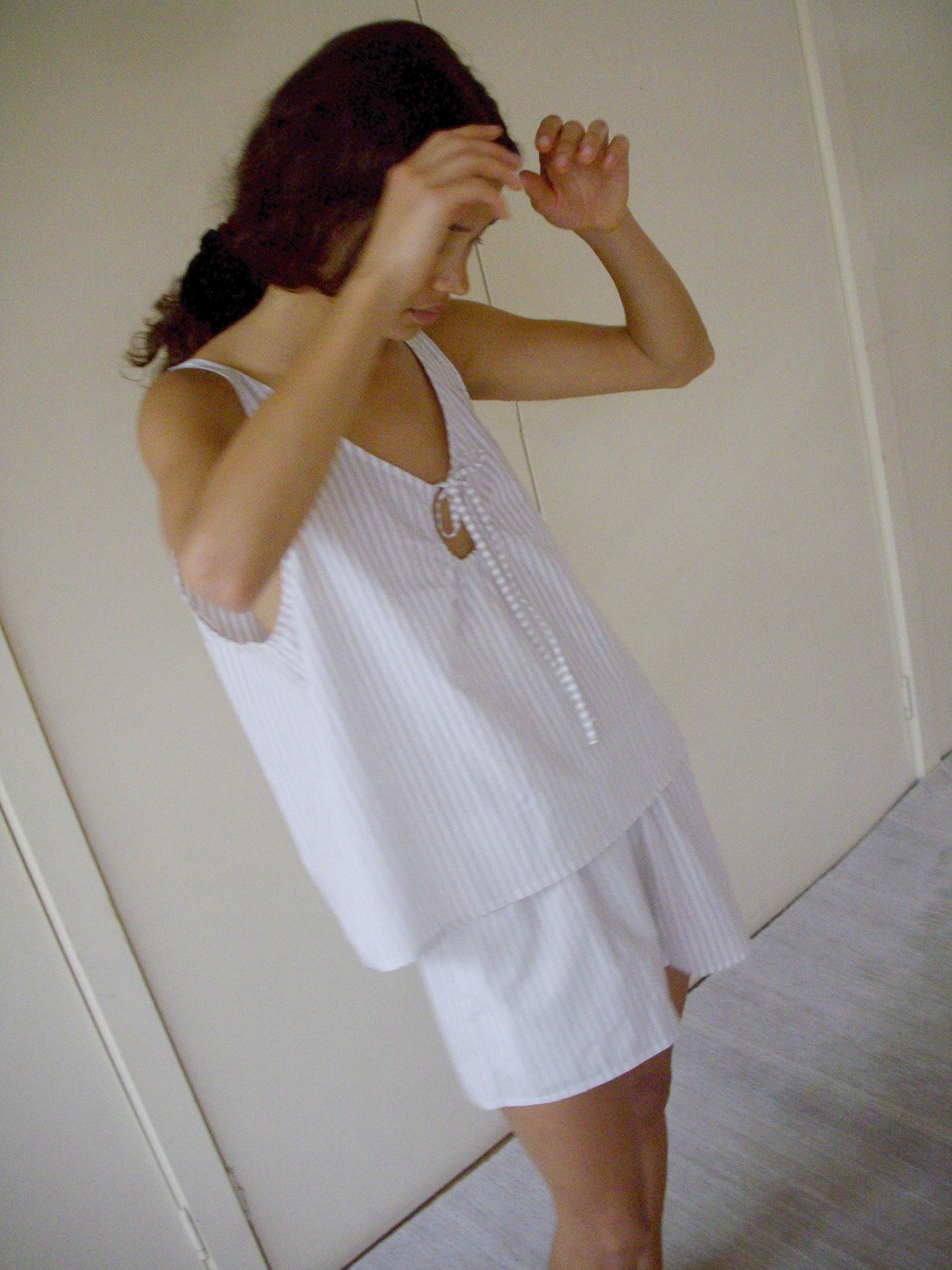 Wearing the U Shape Cotton Set - Lake Stripe, a person stands indoors with arms raised, face partially hidden by hands and hair.