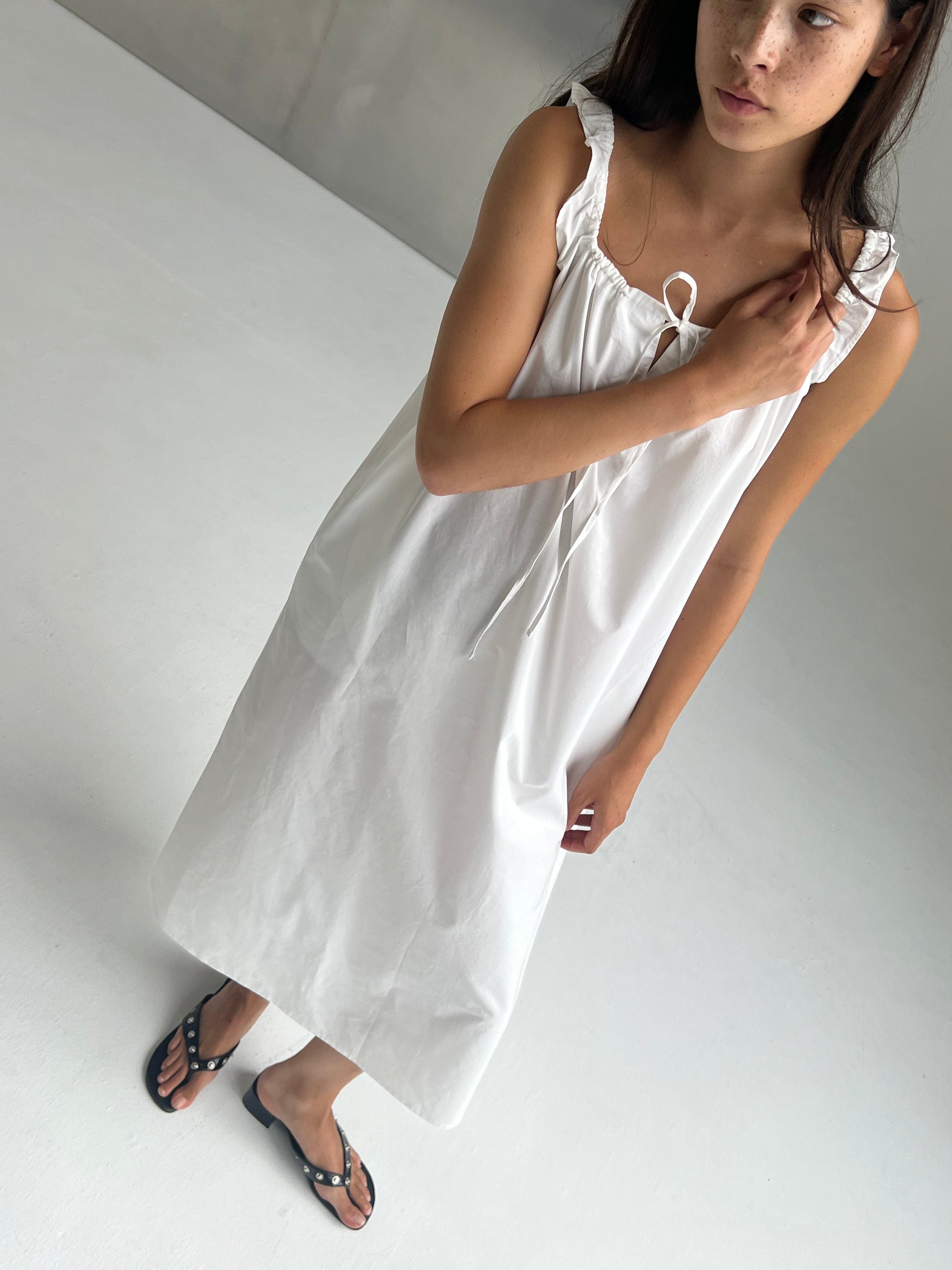 female model wears the paper dress by Deiji Studios in white, a crisp and lightweight maxi-length dress features a flattering gathered square neckline with keyhole and tie front feature and side seam pockets, made from GOTS certified organic cotton poplin
