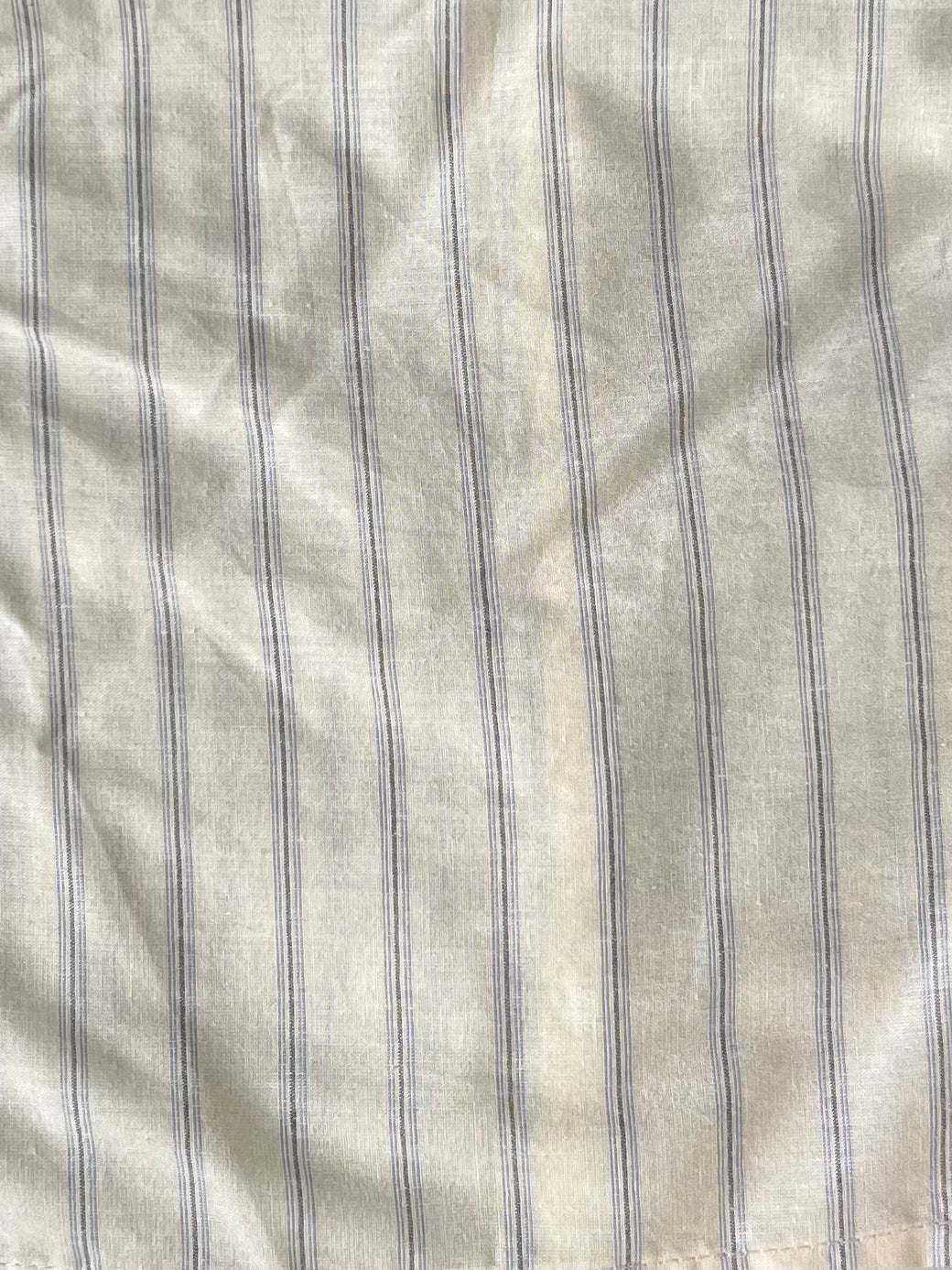 White organic cotton fabric with thin, vertical blue stripes and a softly wrinkled finish—ideal for creating the Ruffle Button Top - Raquette Stripe by Deiji Studios.