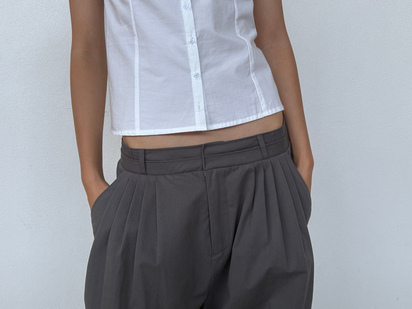 Person wearing a white short-sleeve button-up shirt and 0 Two Layer Pant - Charcoal, standing with hands in pockets against a plain light background.