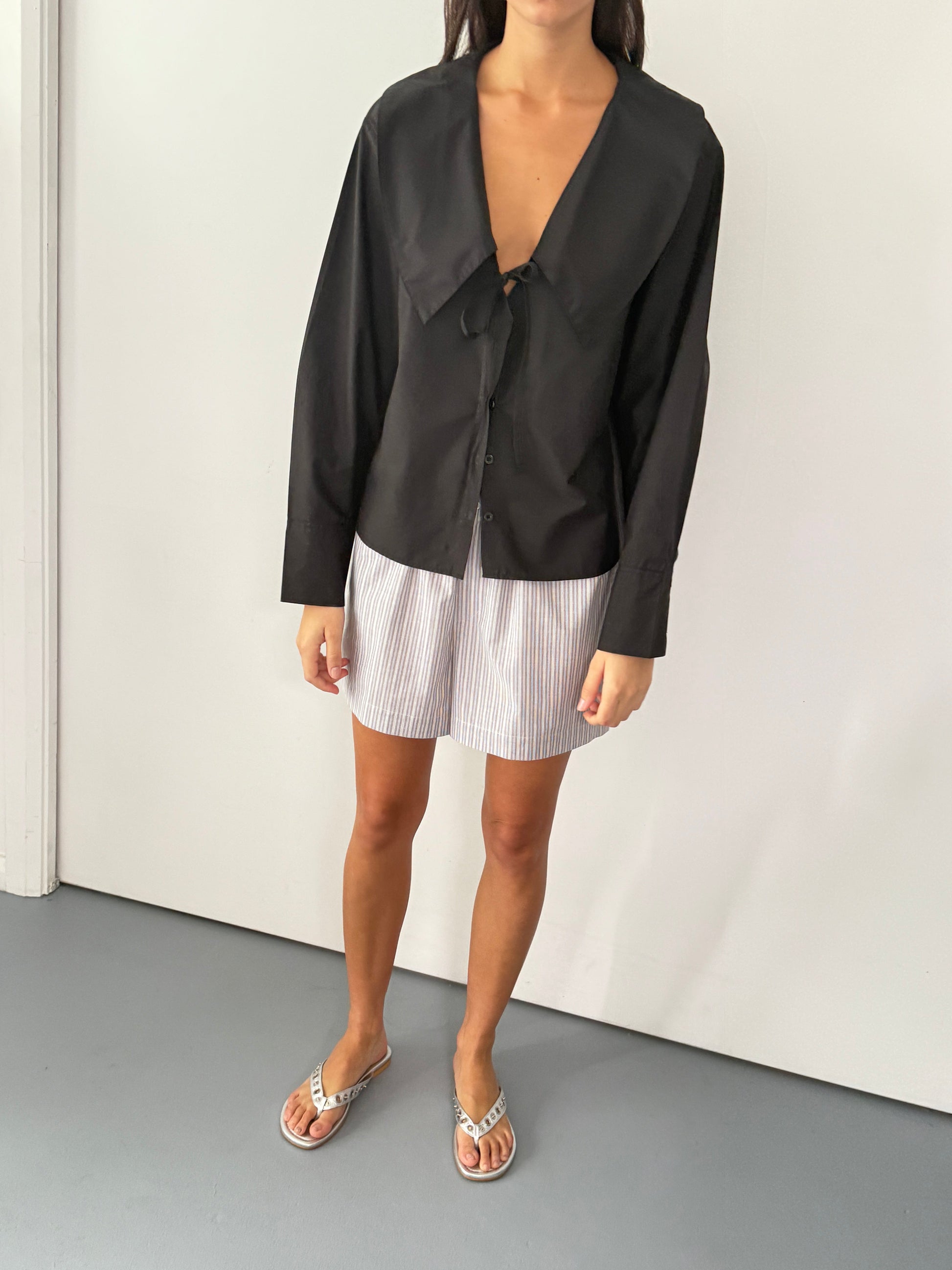 the collared tie shirt by Deiji Studios in black


a structured shirt features an oversized collar and cuff, tie at front collar opening, dropped shoulder and elongated sleeves in a boxy fit


made from 100% GOTS certified organic cotton poplin

paired with a blue stripe cotton boxer