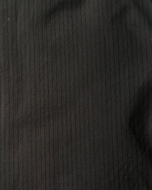 Close-up of the Layered Short - Black Stripe by 0, featuring smooth dark black fabric with subtle vertical pinstripes, crafted from organic cotton and showing soft folds.