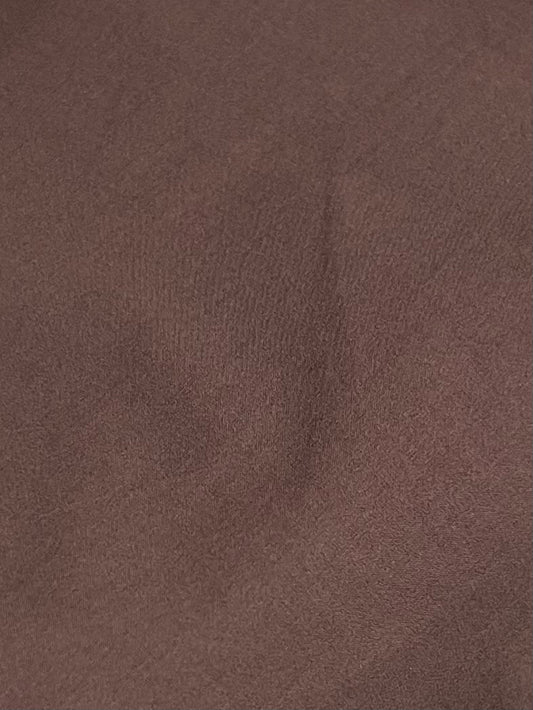 A close-up of the Button Skirt - Chocolate shows brown organic cotton fabric with subtle creases and shadows, creating an uneven texture that reflects Deiji Studios signature relaxed style.