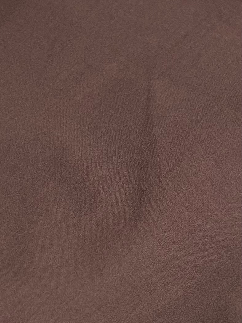 A close-up of the Button Skirt - Chocolate shows brown organic cotton fabric with subtle creases and shadows, creating an uneven texture that reflects Deiji Studios signature relaxed style.
