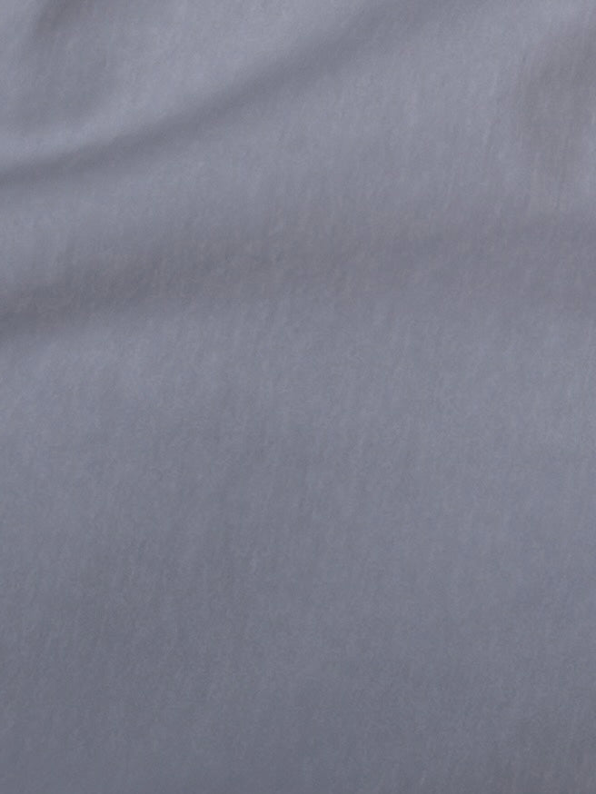 A close-up of the soft, smooth light gray organic cotton fabric of the Two Band Pant - Cornflower, showing gentle folds and subtle texture—ideal for relaxed trousers.