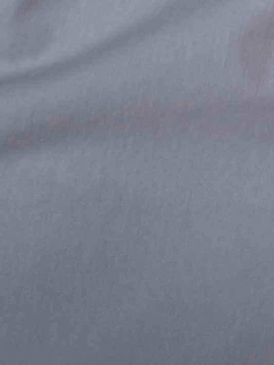 A close-up of the soft, smooth light gray organic cotton fabric of the Two Band Pant - Cornflower, showing gentle folds and subtle texture—ideal for relaxed trousers.