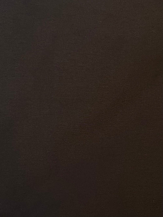 A close-up of the Press Stud Saddle Bag in Dark Chocolate shows a richly textured, dark brown surface with subtle shading, echoing sculptural elements of premium design.