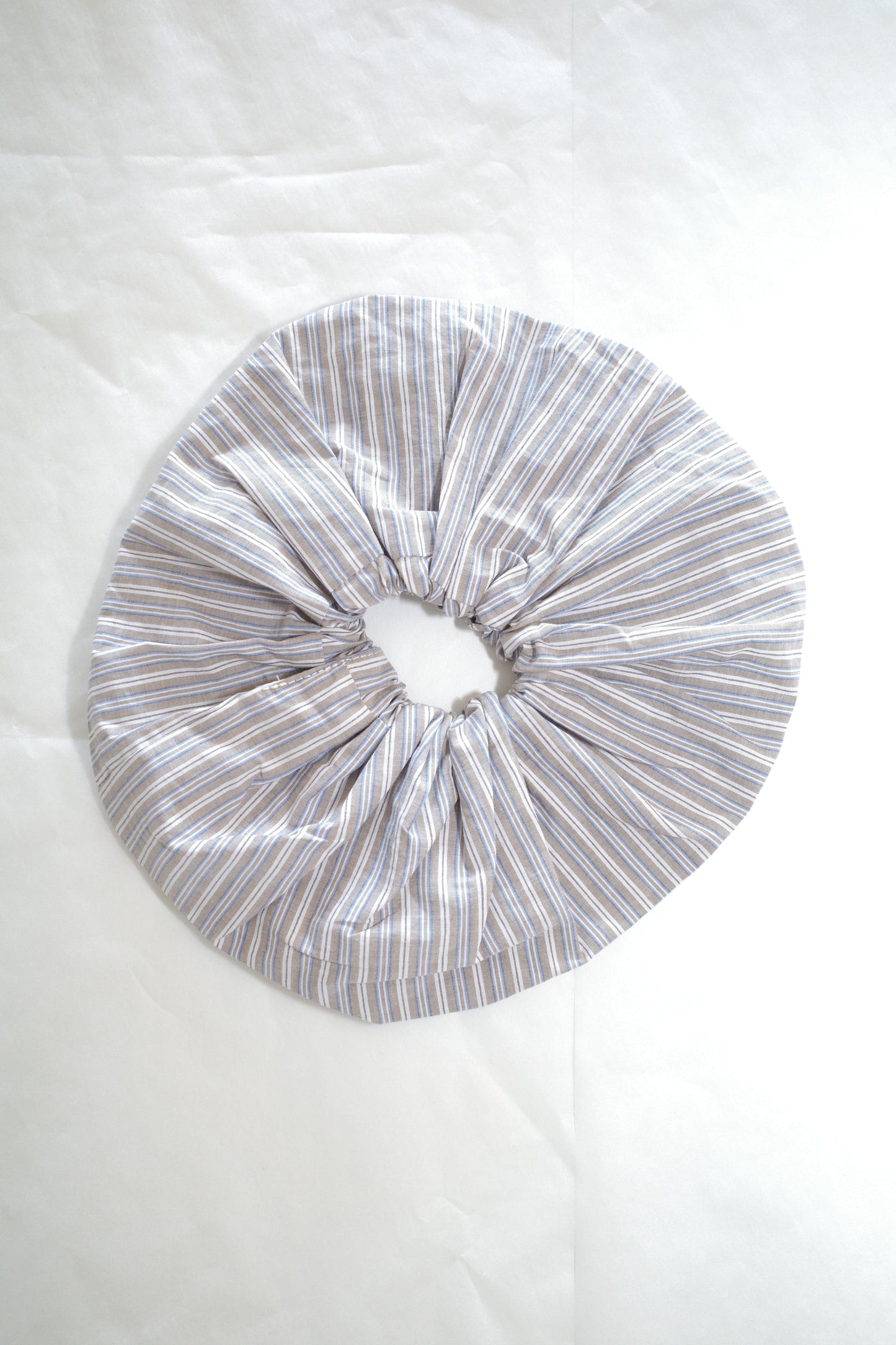 The Scrunchie - Seas Stripe by Deiji Studios is an oversized scrunchie made from organic cotton, featuring thin grey and white vertical stripes, shown on a white background.