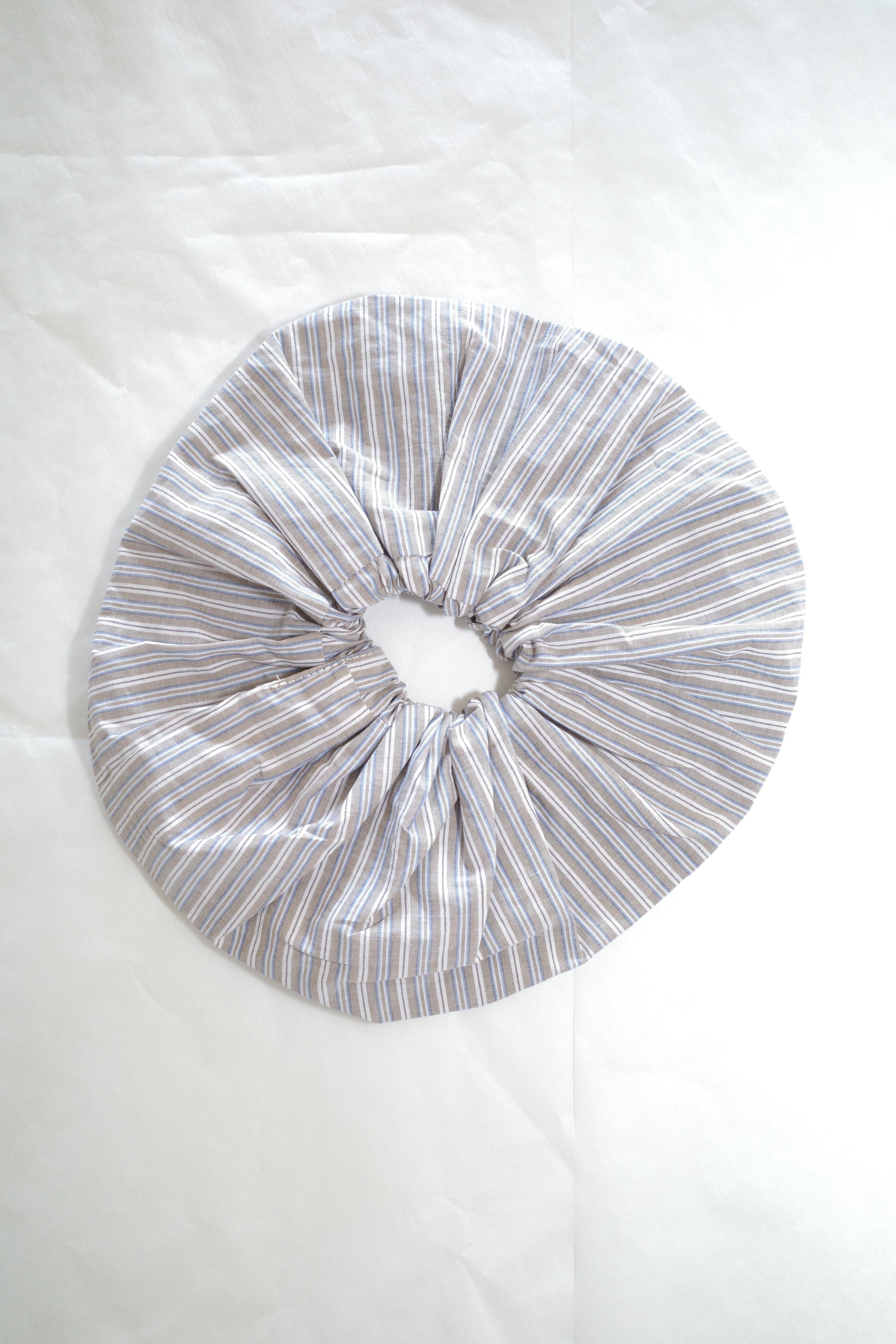 The Scrunchie - Seas Stripe by Deiji Studios is an oversized scrunchie made from organic cotton, featuring thin grey and white vertical stripes, shown on a white background.