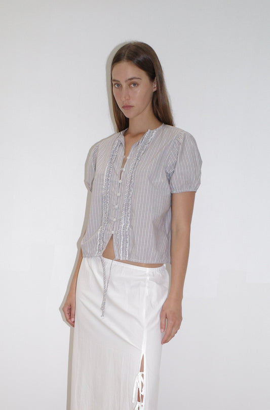 female model wears the double frill top by Deiji Studios in seas stripe



elevated everyday top features a flattering v neckline with button down front, fixed ruffle details, soft blouson sleeve and gathered elastic cuffs


made from 100% GOTS certified organic cotton poplin

paired with a white skirt