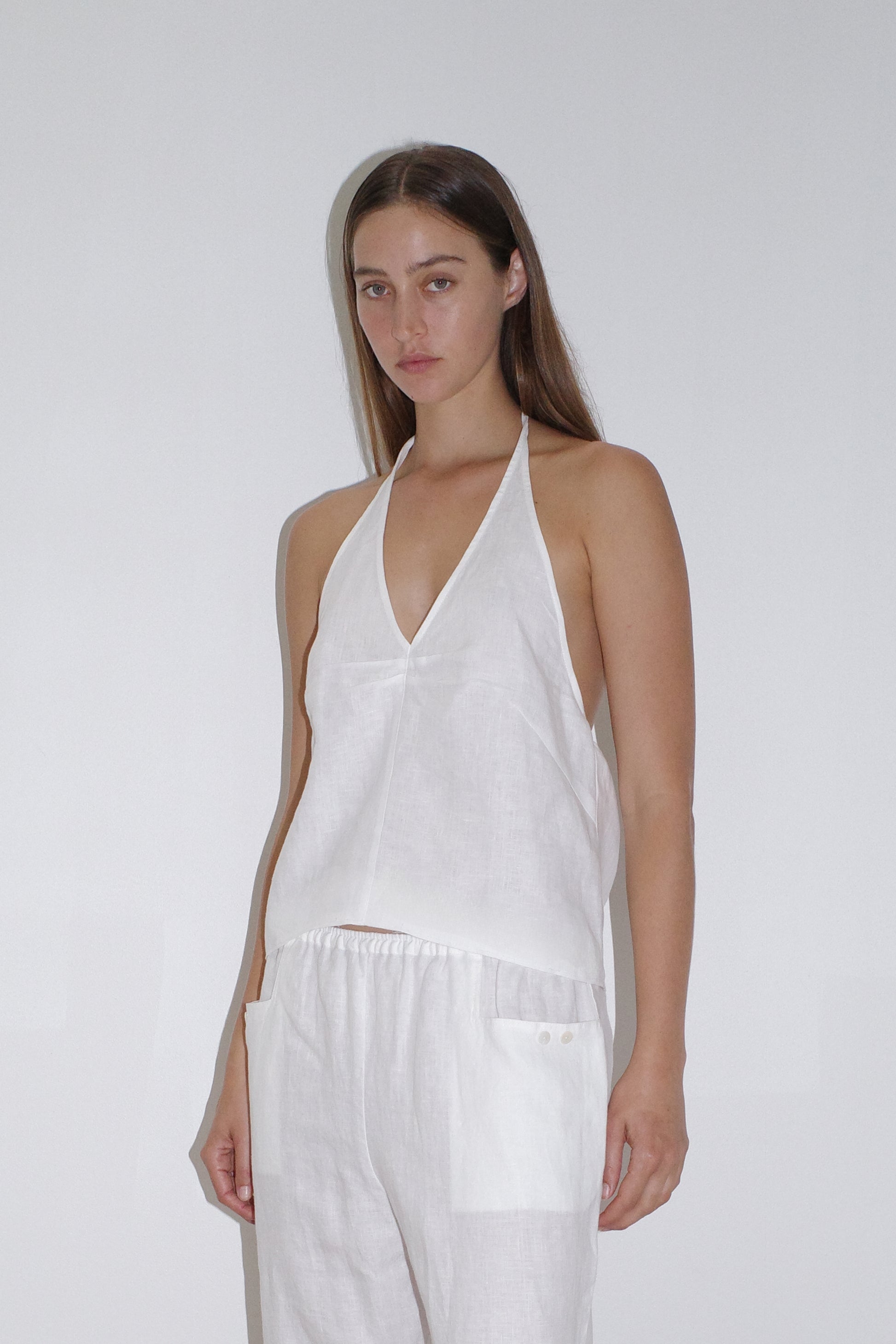 female model wears the linen halter top by Deiji Studios in white

relaxed halter top features flattering v neckline, centre bust pleats and adjustable backline with drawcord tie closure

made from 100% OEKO-TEX 100 certified and EU certified stone washed french linen

paired with a white linen trouser