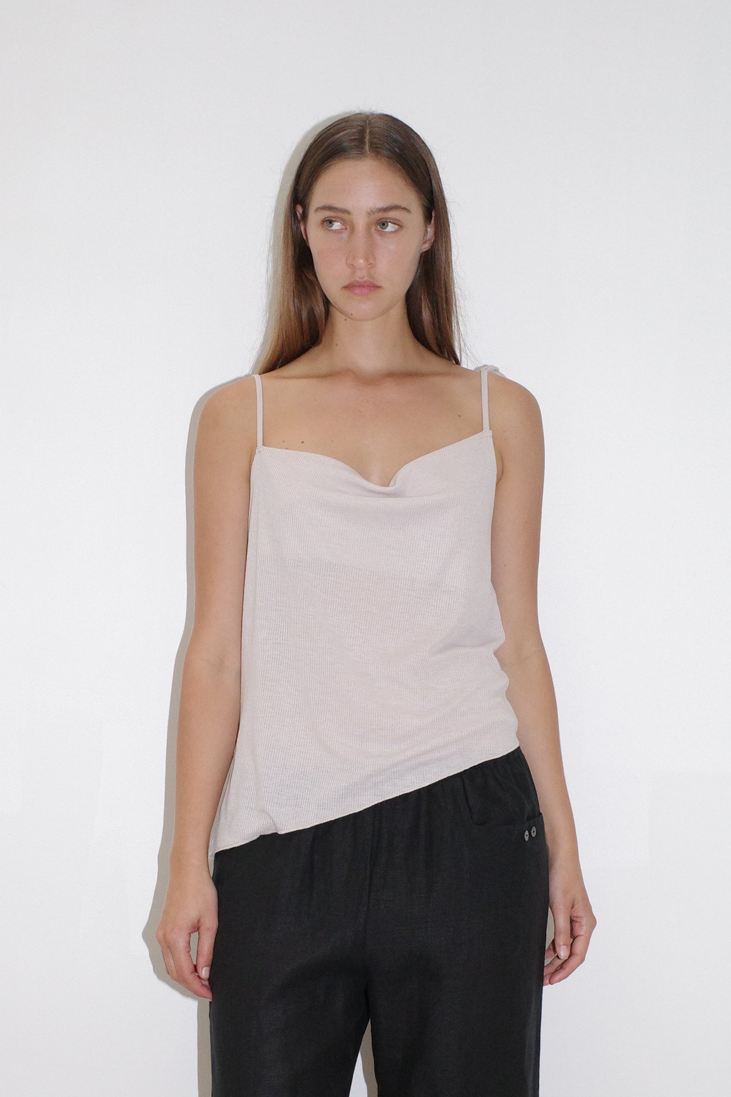 female model wears the split top by Deiji Studios in shell


a sheer fine knit relaxed tank with a fold over cowl neckline and low draping back, features self fabric rouleau straps, baby lock hem finishes and a asymmetric bottom detail


made from a responsible blend of 85% Recycled Polyester and 15% Viscose

paired with a black linen pant