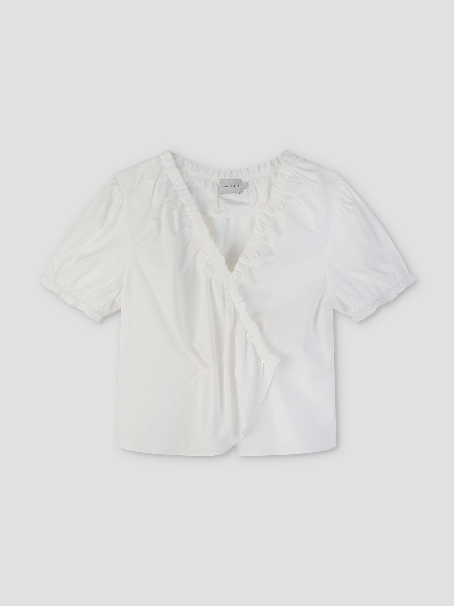 The Cross Frill Top - White features short sleeves, a V-neckline with ruffle trim, a buttoned wrap front, and a cropped relaxed fit in crisp fabric for effortless style.