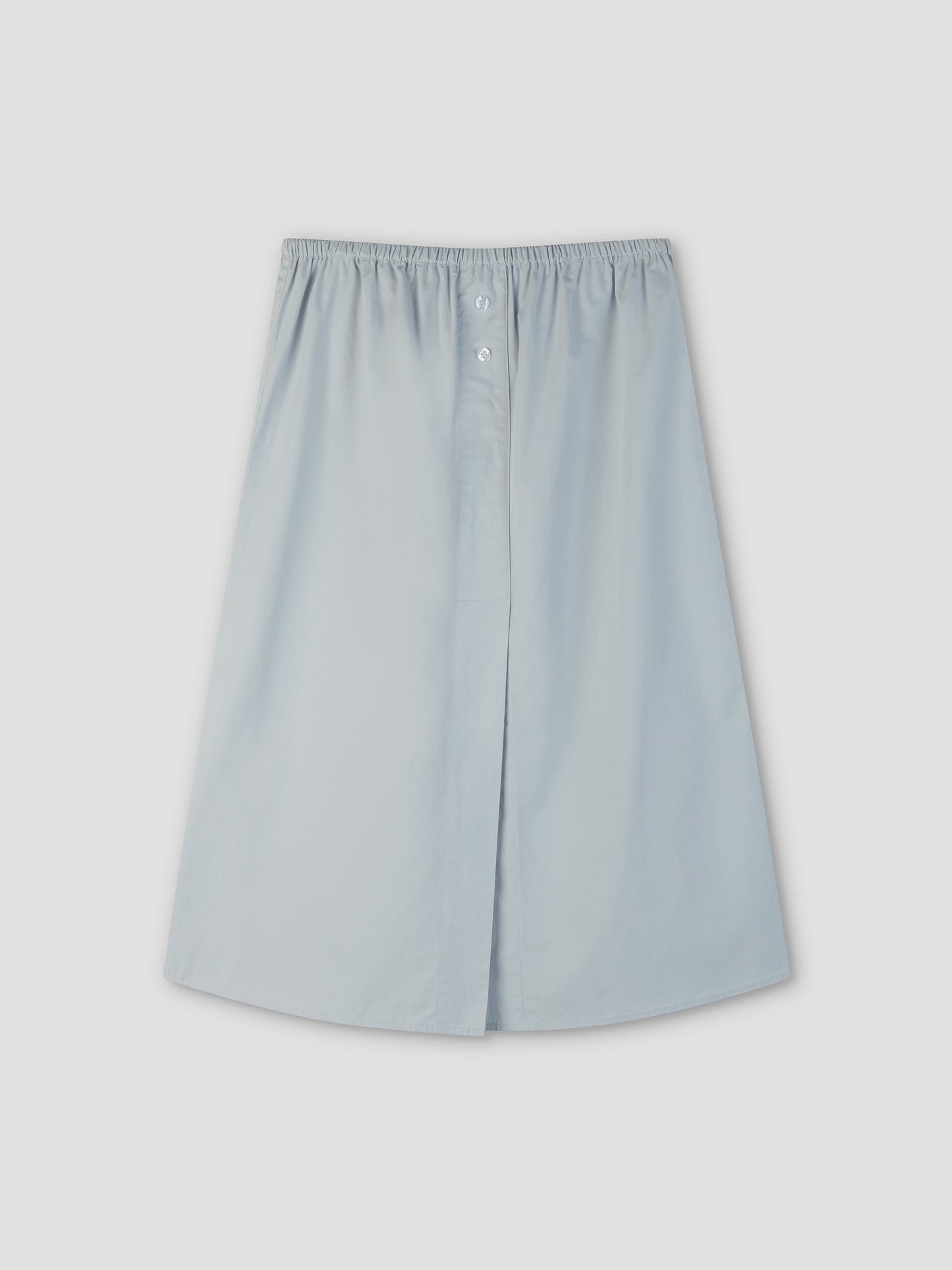 The Overlap Skirt - Blue by Deiji Studios is a light blue, knee-length A-line skirt with an elastic waistband and front button detail, shown on a plain light gray background.