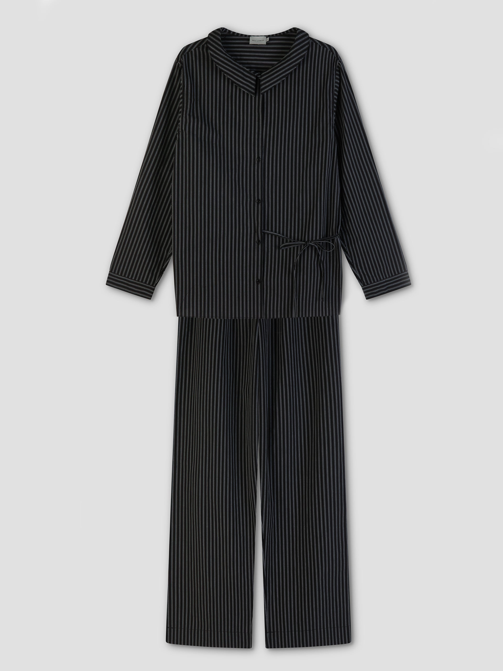 The Left Set - Mono Stripe features black pajamas with thin white stripes, including a lightweight, relaxed-fit long-sleeve button-up shirt and matching pants, displayed flat on a light gray background.