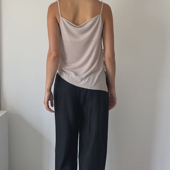 female model wears the split top by Deiji Studios in shell


a sheer fine knit relaxed tank with a fold over cowl neckline and low draping back, features self fabric rouleau straps, baby lock hem finishes and a asymmetric bottom detail


made from a responsible blend of 85% Recycled Polyester and 15% Viscose

paired with a black cotton skirt