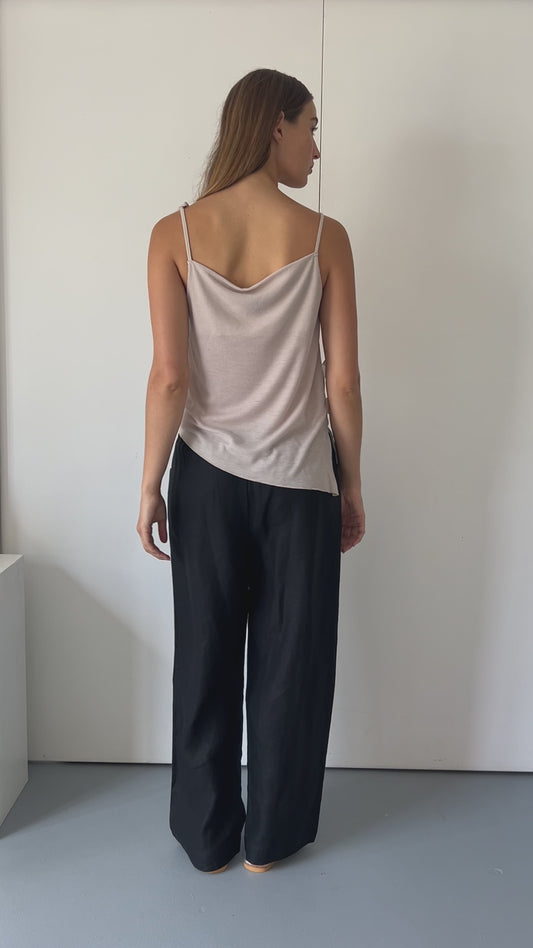 female model wears the split top by Deiji Studios in shell


a sheer fine knit relaxed tank with a fold over cowl neckline and low draping back, features self fabric rouleau straps, baby lock hem finishes and a asymmetric bottom detail


made from a responsible blend of 85% Recycled Polyester and 15% Viscose

paired with a black cotton skirt